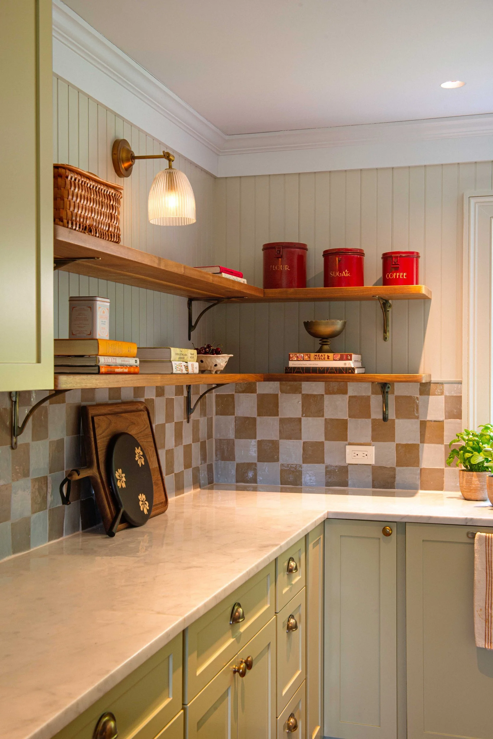 Silvernails kitchen corner with sage cabinetry, a checkered backsplash and brass wall lamp