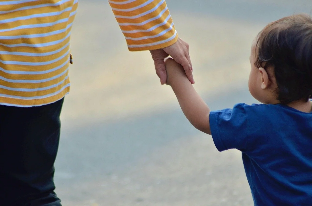 A mother holds hands with her child. Is unhealed trauma affecting how you parent? Working with a therapist for moms in Mill Creek, WA, can guide you through healing while helping you navigate motherhood with support.