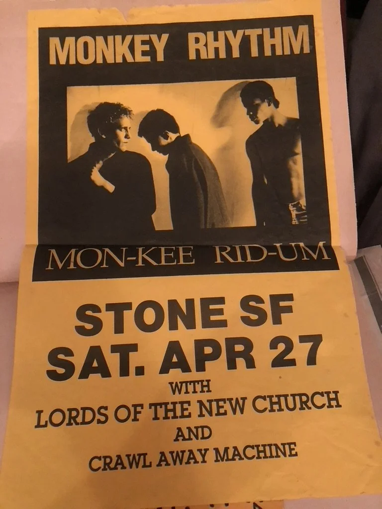 A yellow and black poster for a music event featuring the band Monkey Rhythm. The poster includes a black-and-white photo of three band members with distinct hair and physiques. The event is scheduled for Saturday, April 27 at Stone SF, with addition