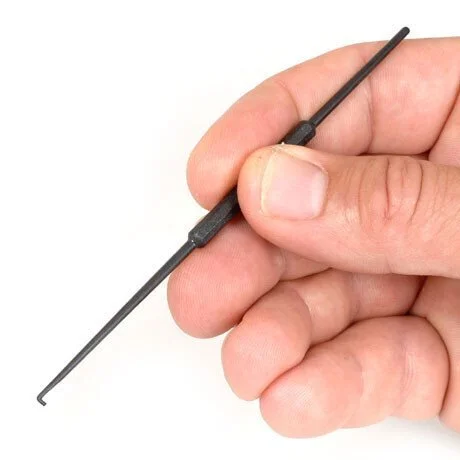 A hand holding a small, dark screwdriver with a textured grip, used for precise tasks.