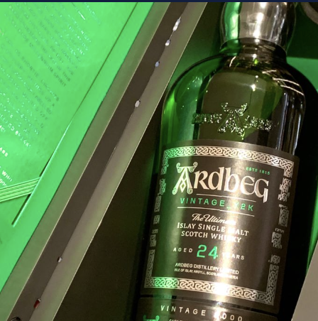 Close-up of a bottle of Ardbeg Vintage 1997 Scotch whisky on a green background.