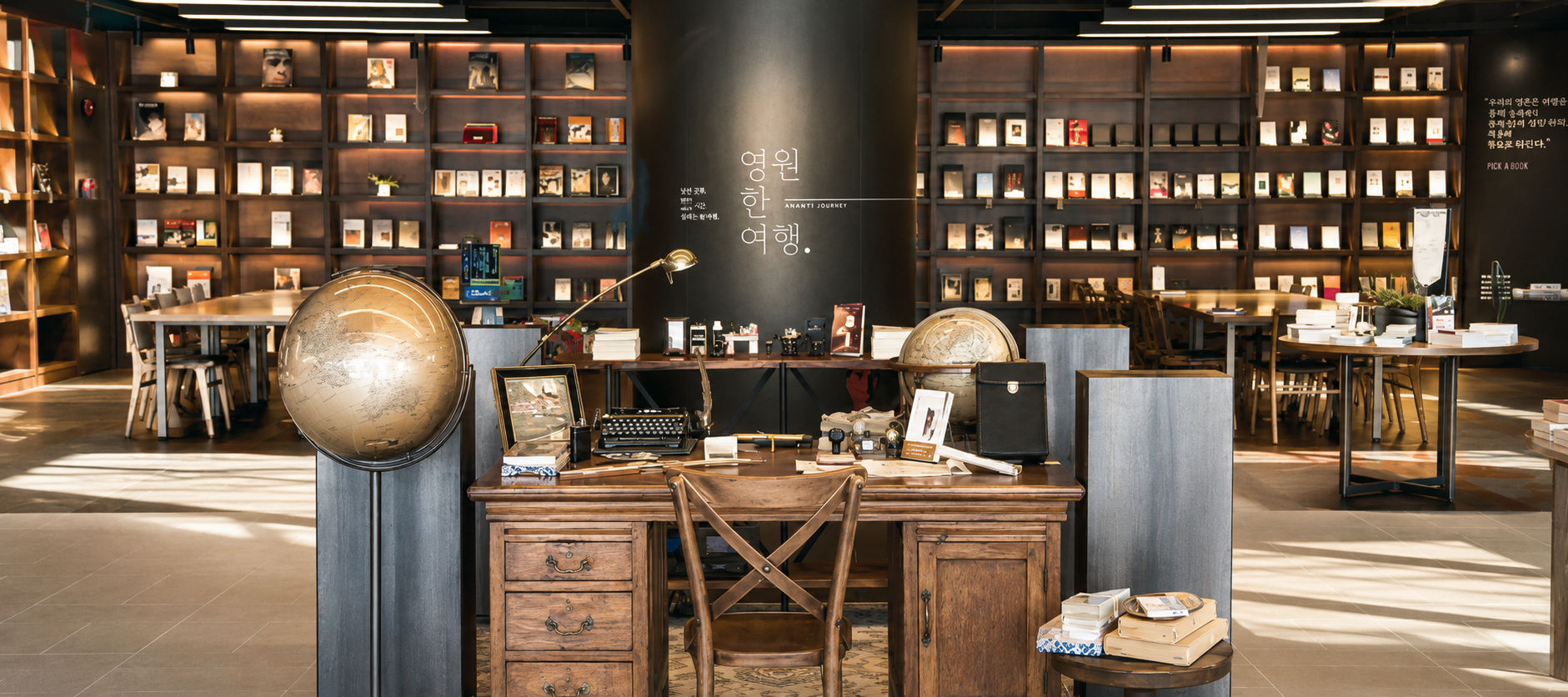 Interior del centro cultural Eternal Journey en el Hotel Ananti de Busan, mostrando estanterías de madera repletas de libros, globos terráqueos y un escritorio clásico de madera.