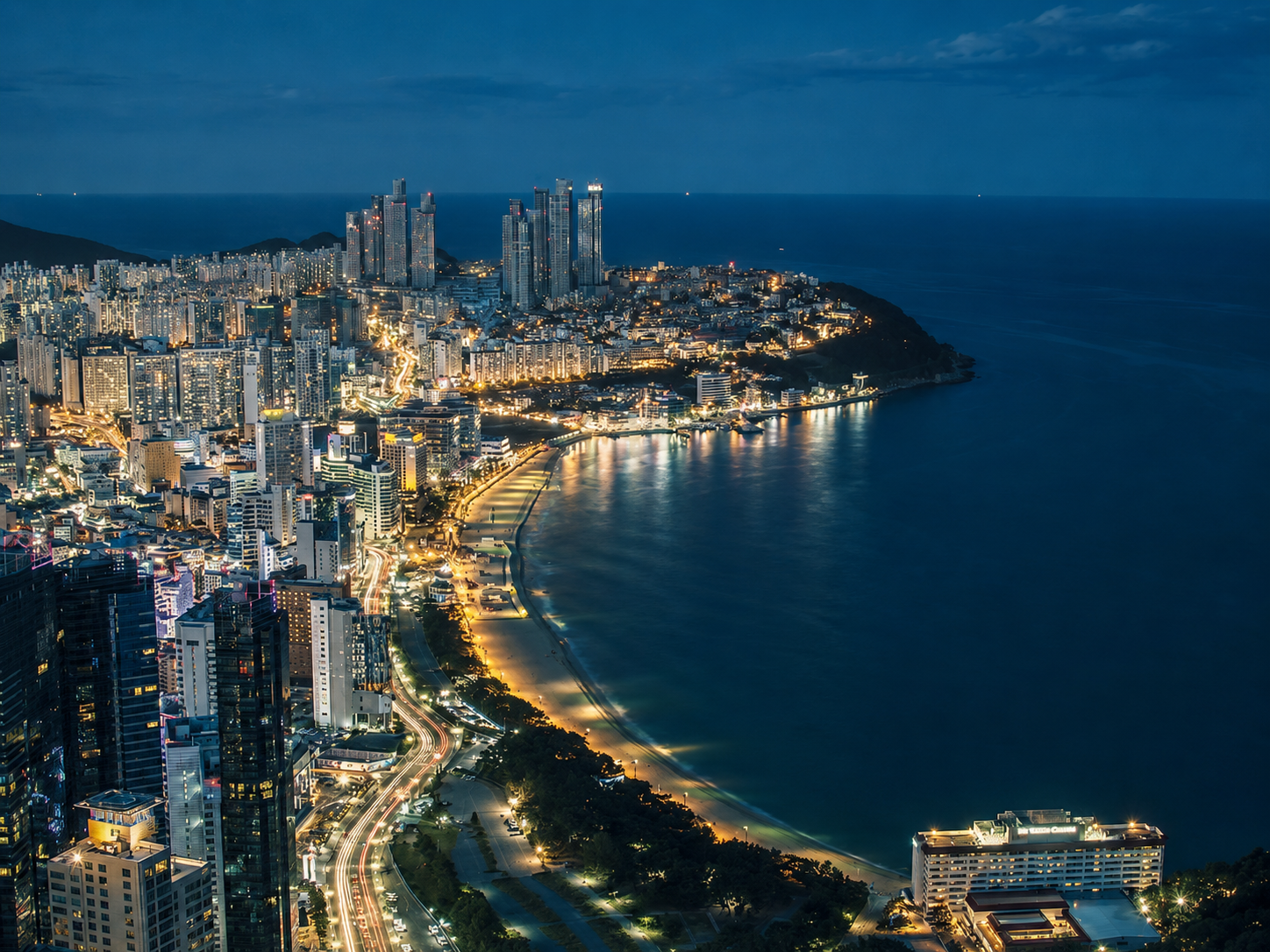 Vista panorámica nocturna de la costa y rascacielos iluminados en Busan, Corea del Sur, cerca del hotel de lujo Ananti Cove.