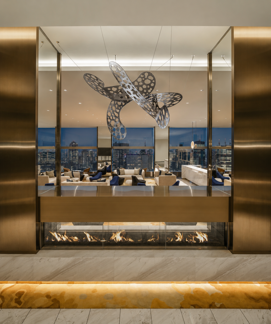 Interiorismo contemporáneo del lobby de recepción en The Prince Gallery Tokyo Kioicho con chimenea lineal y acabados de mármol.