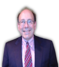 A middle-aged man wearing glasses, a dark suit, a light-colored shirt, and a tie with red and blue pattern, smiling against a plain white background.