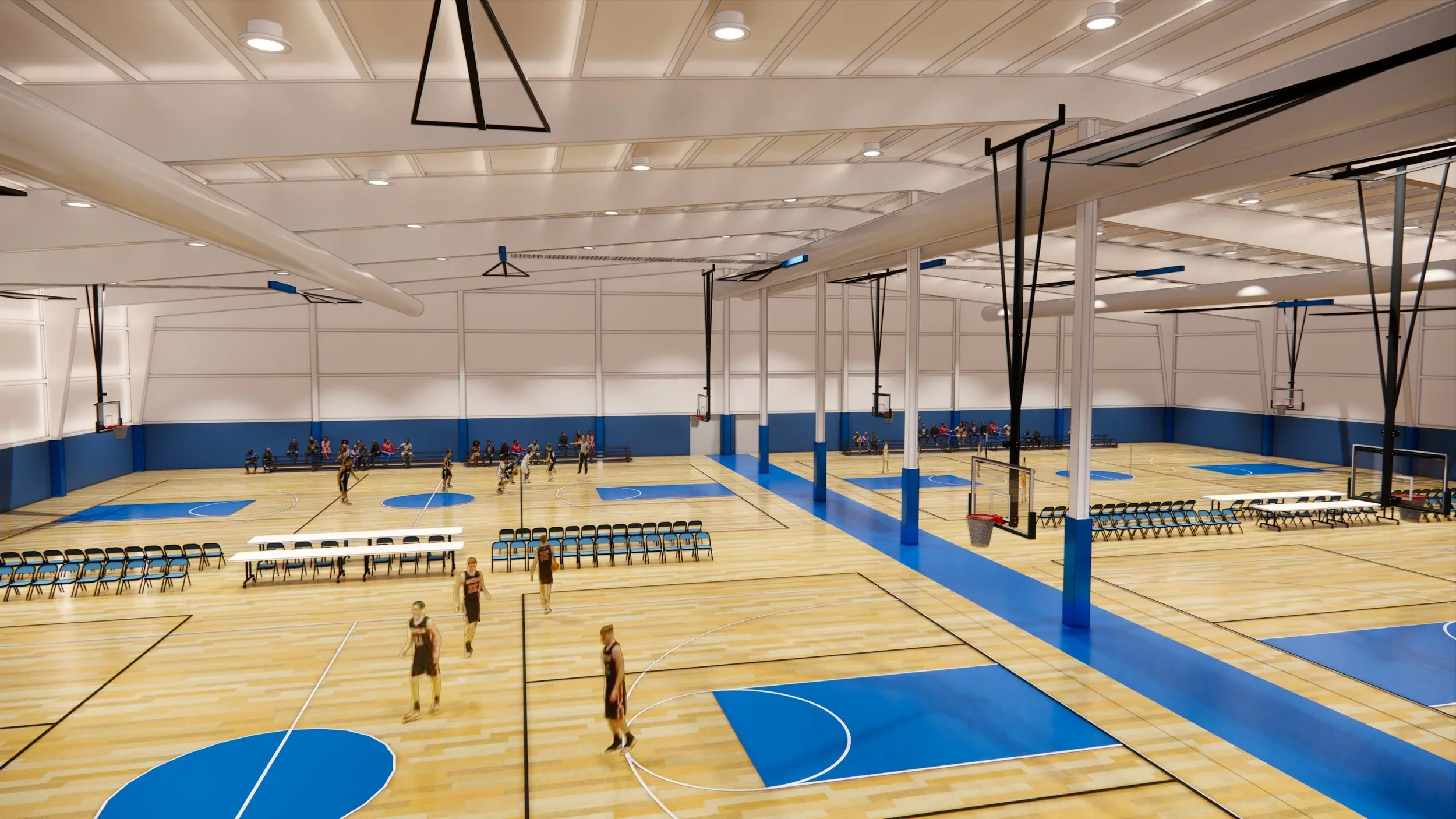 Indoor basketball court with players practicing, spectators seated along the sides, and seating arrangements on the sidelines.