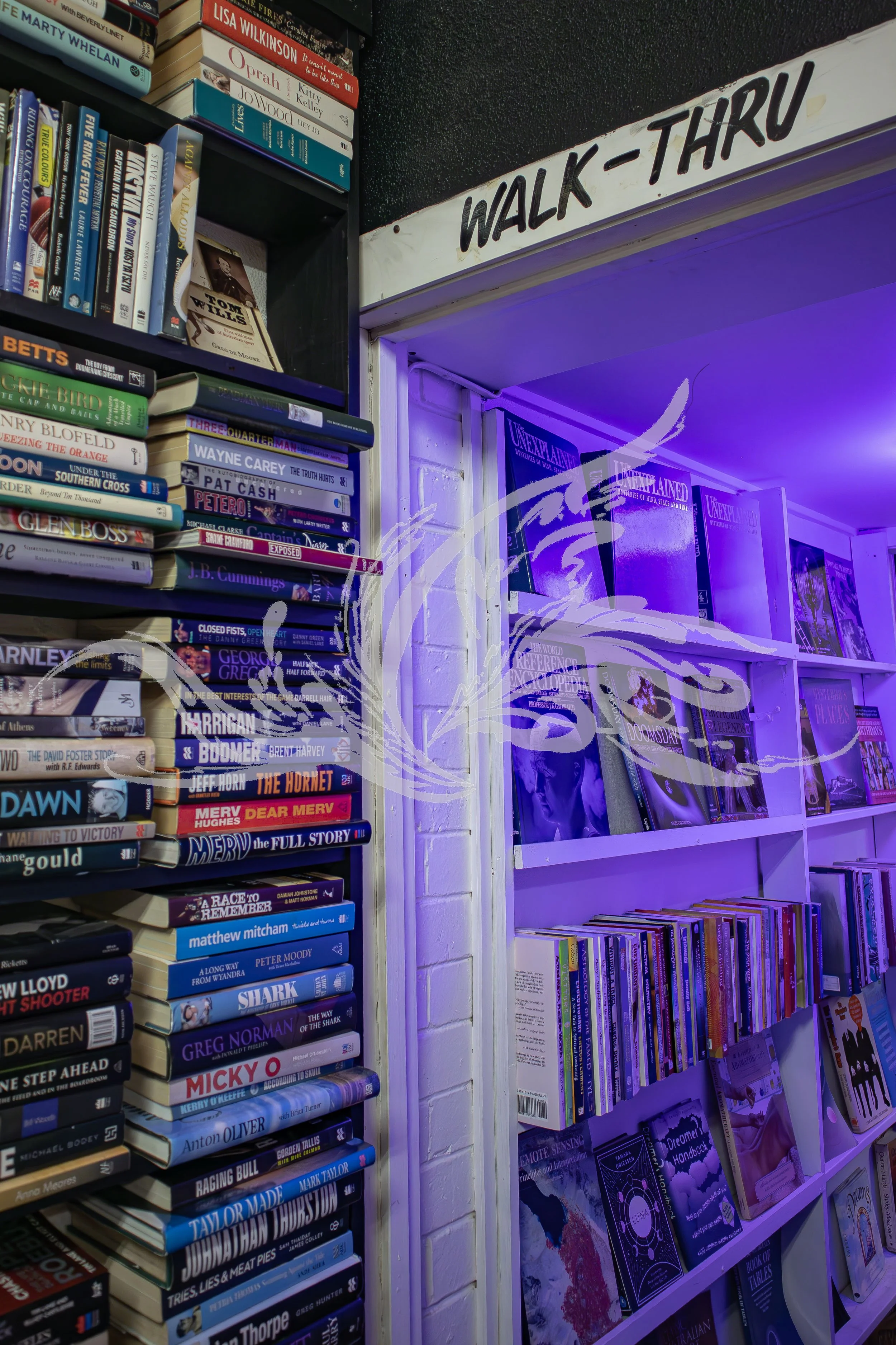 Bookshelves filled with books, a sign reading 'Walk-Thru', and purple lighting illuminating the area.
