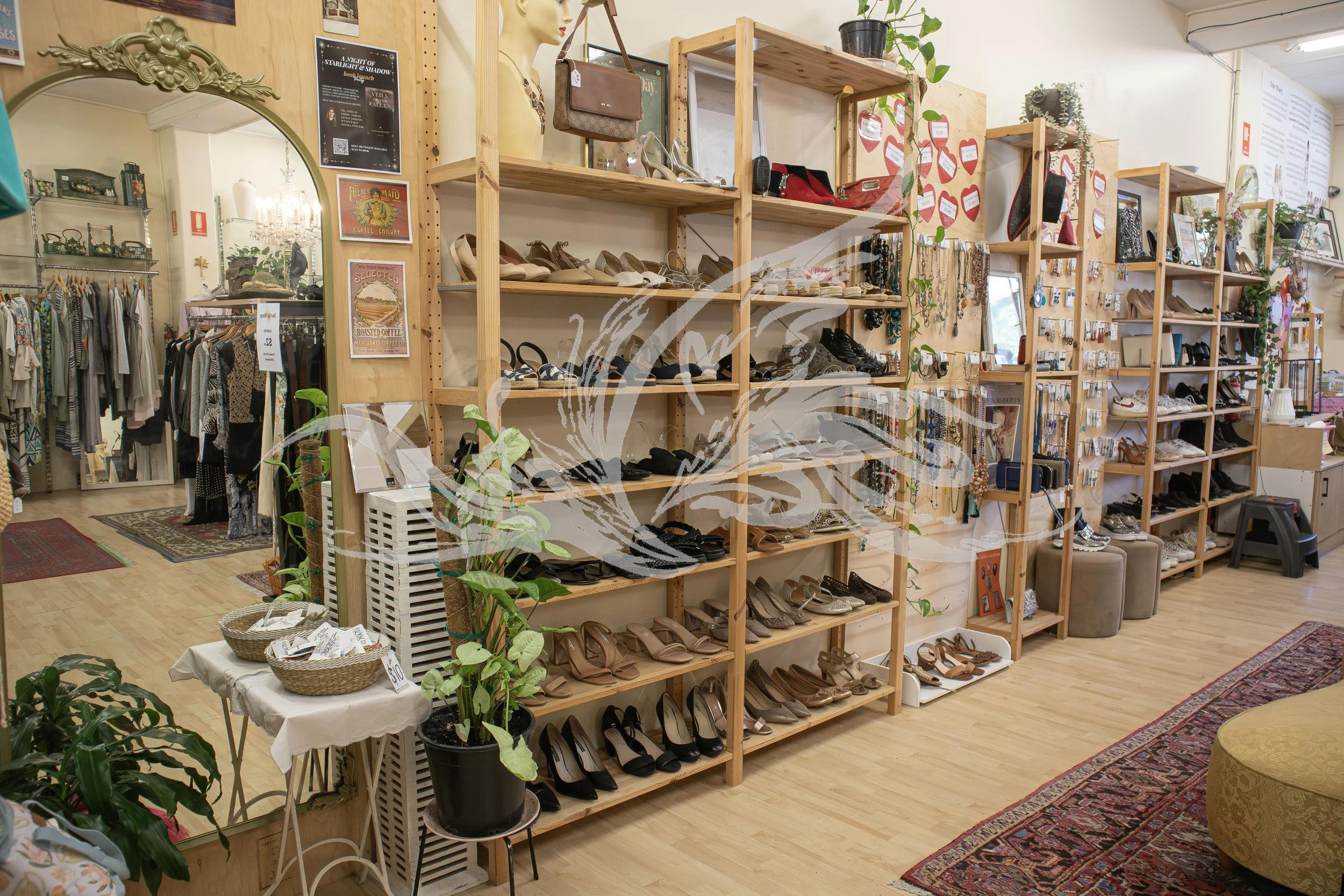 A store with wooden shelves displaying shoes, handbags, jewelry, and accessories. The store has a wooden floor, plants, and decorative rugs.