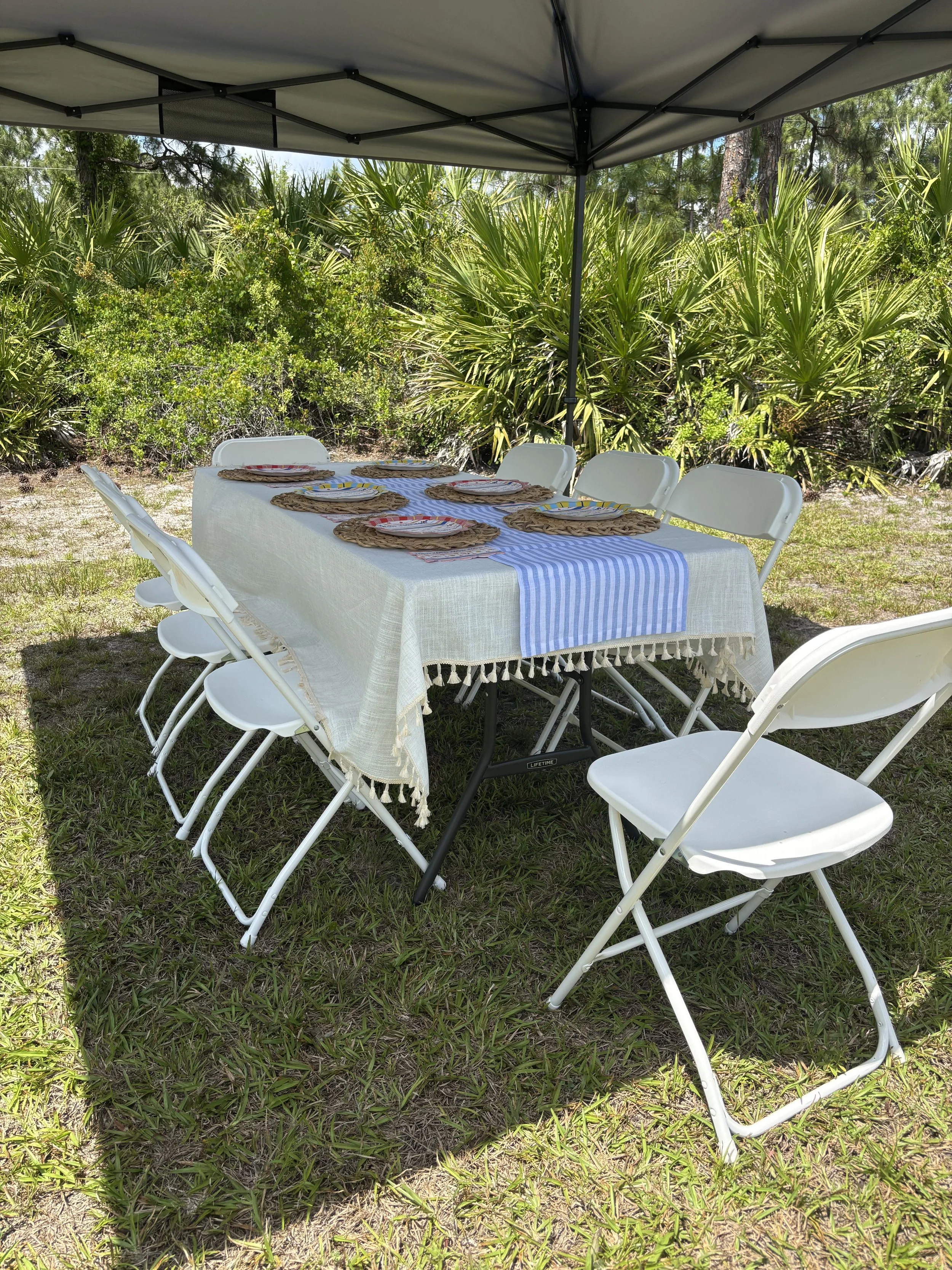 White folding chairs and tables set up outdoors at golden hour — Saltwater Event Co. event rentals, Treasure Coast Florida