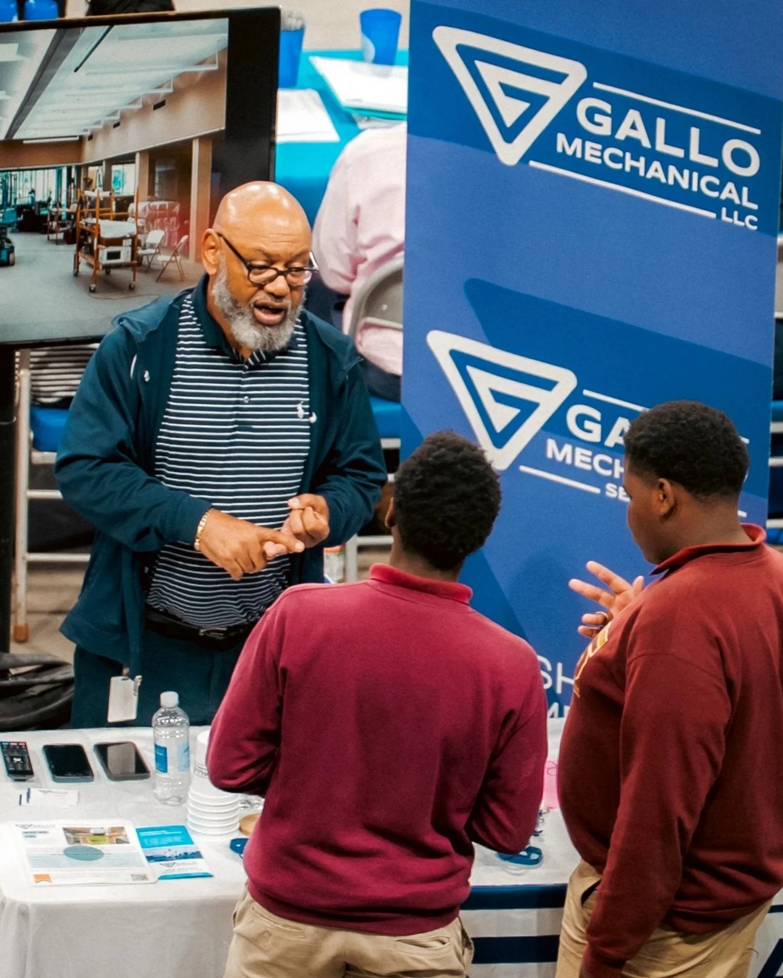 Business partner explains how to prepare for a career in the industry to two students at Career Expo