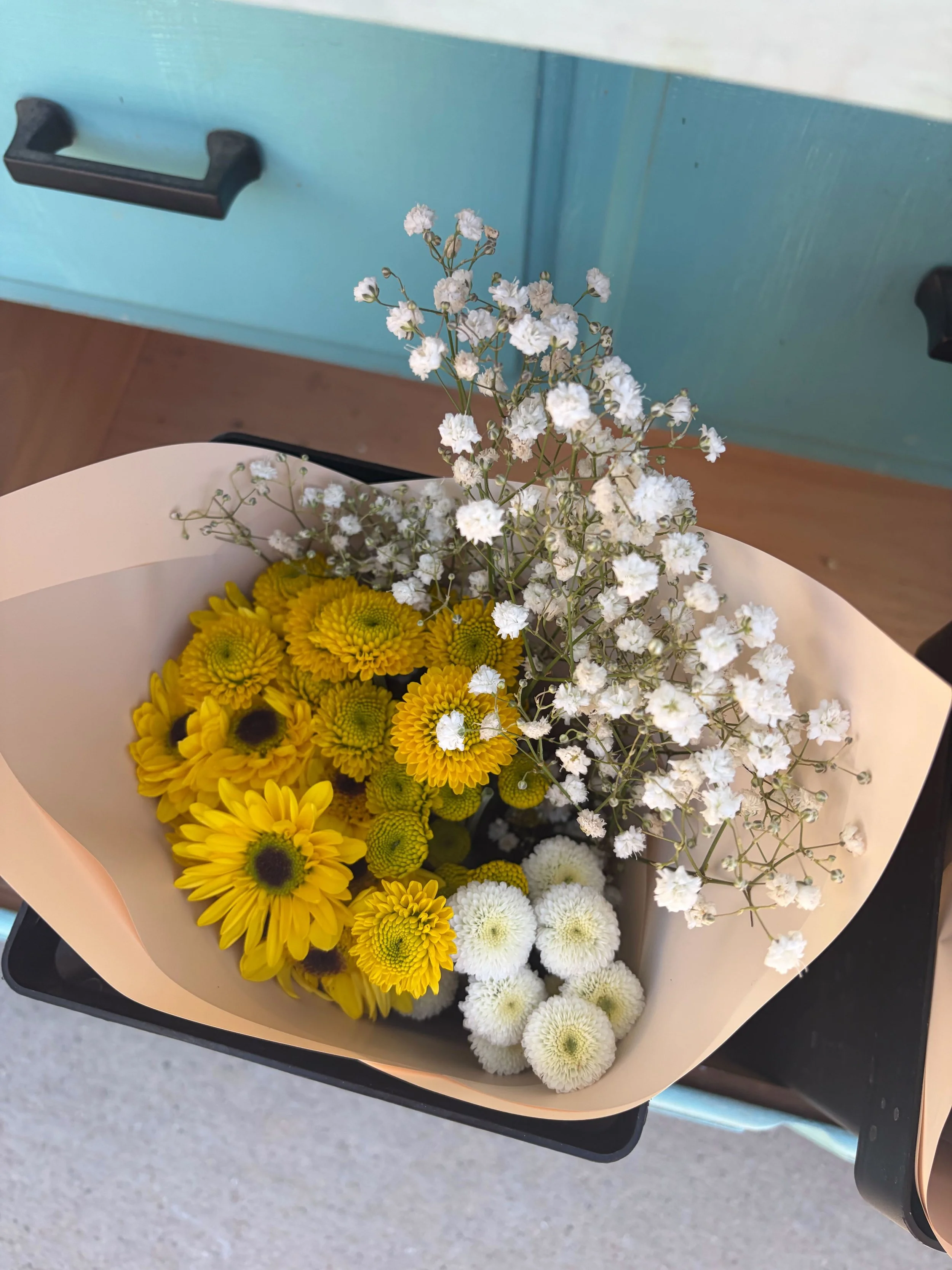 Bouquet of yellow and white flowers with white baby's breath in decorative pink wrapping