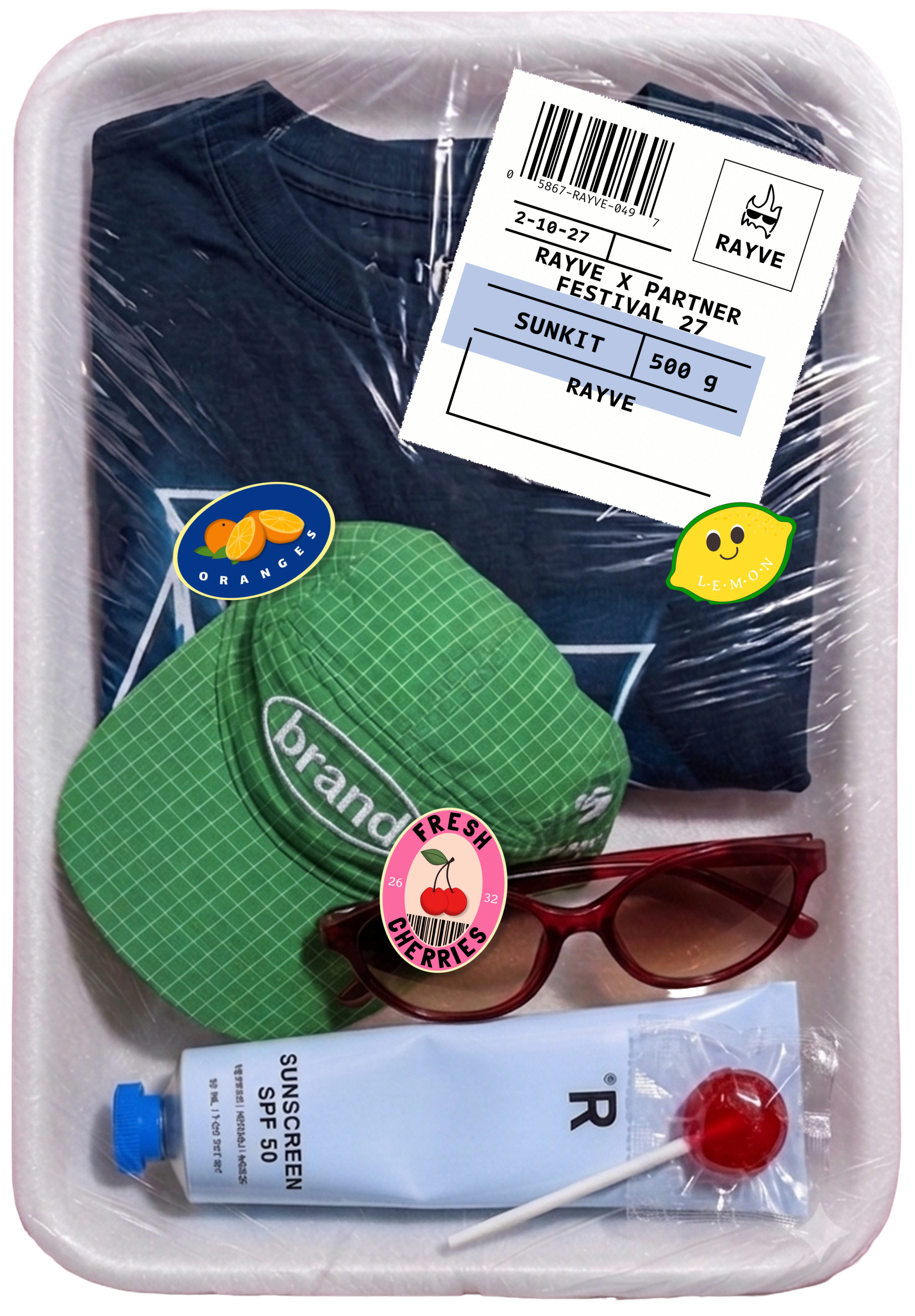 A trendy themed sun-kit containing a dark blue t-shirt, a green fabric hat with the word 'brand,' a tube of sunscreen SPF 50, red sunglasses, and a red lollipop. The kit has plastic wrap and various stickers with fruit images.