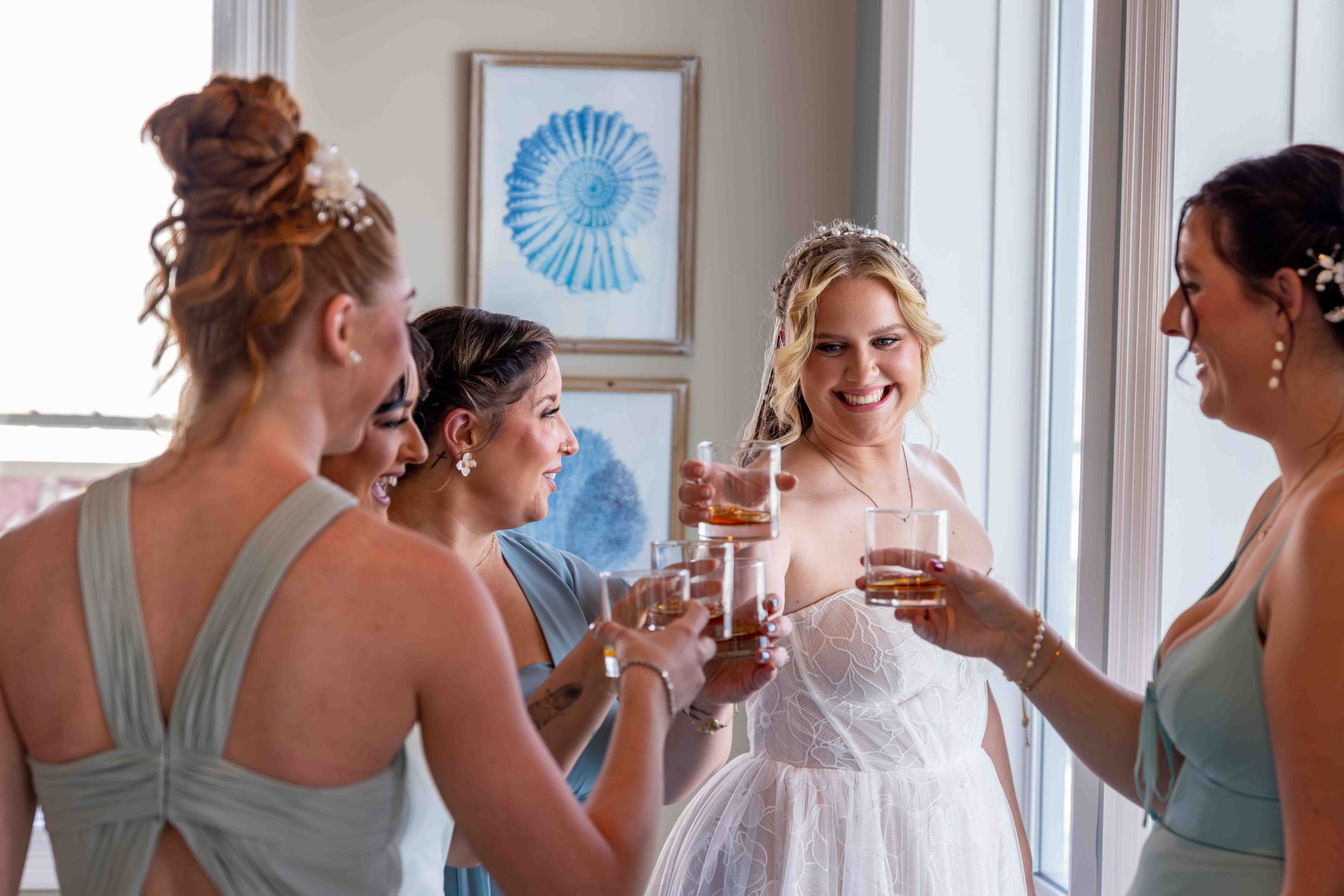 Group of women dressed in bridesmaid dresses clinking glasses with champagne in celebration.