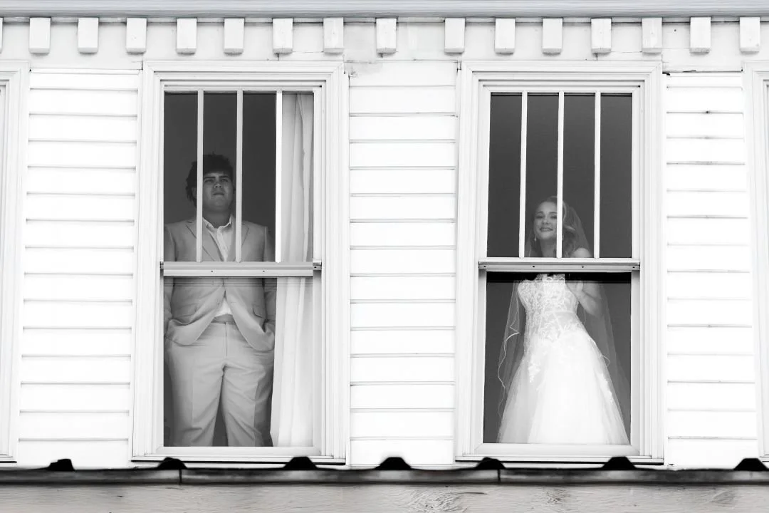 A double window shot of the groom on the left and the bride on the right both looking out the window. Gulf Shores Wedding Photographer