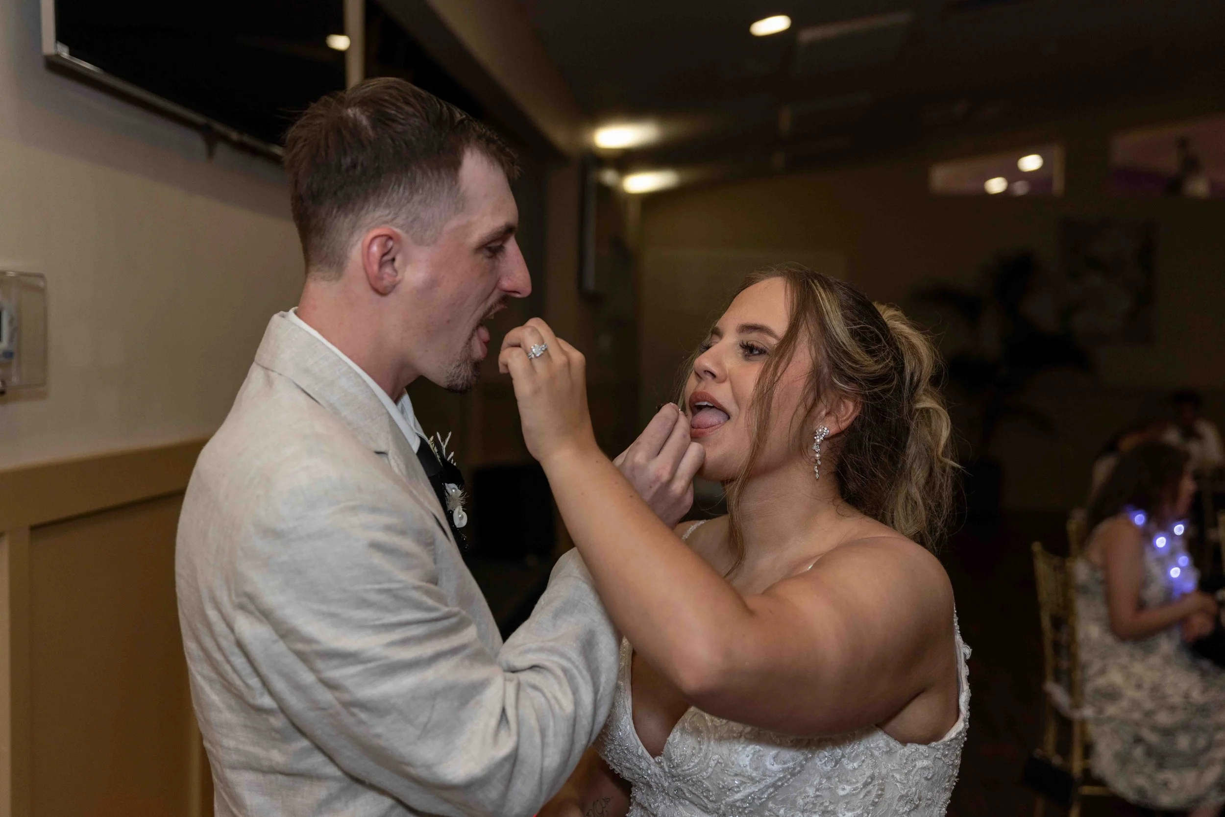 A bride and groom dance at their wedding reception, with the bride touching the groom's face and both smiling.