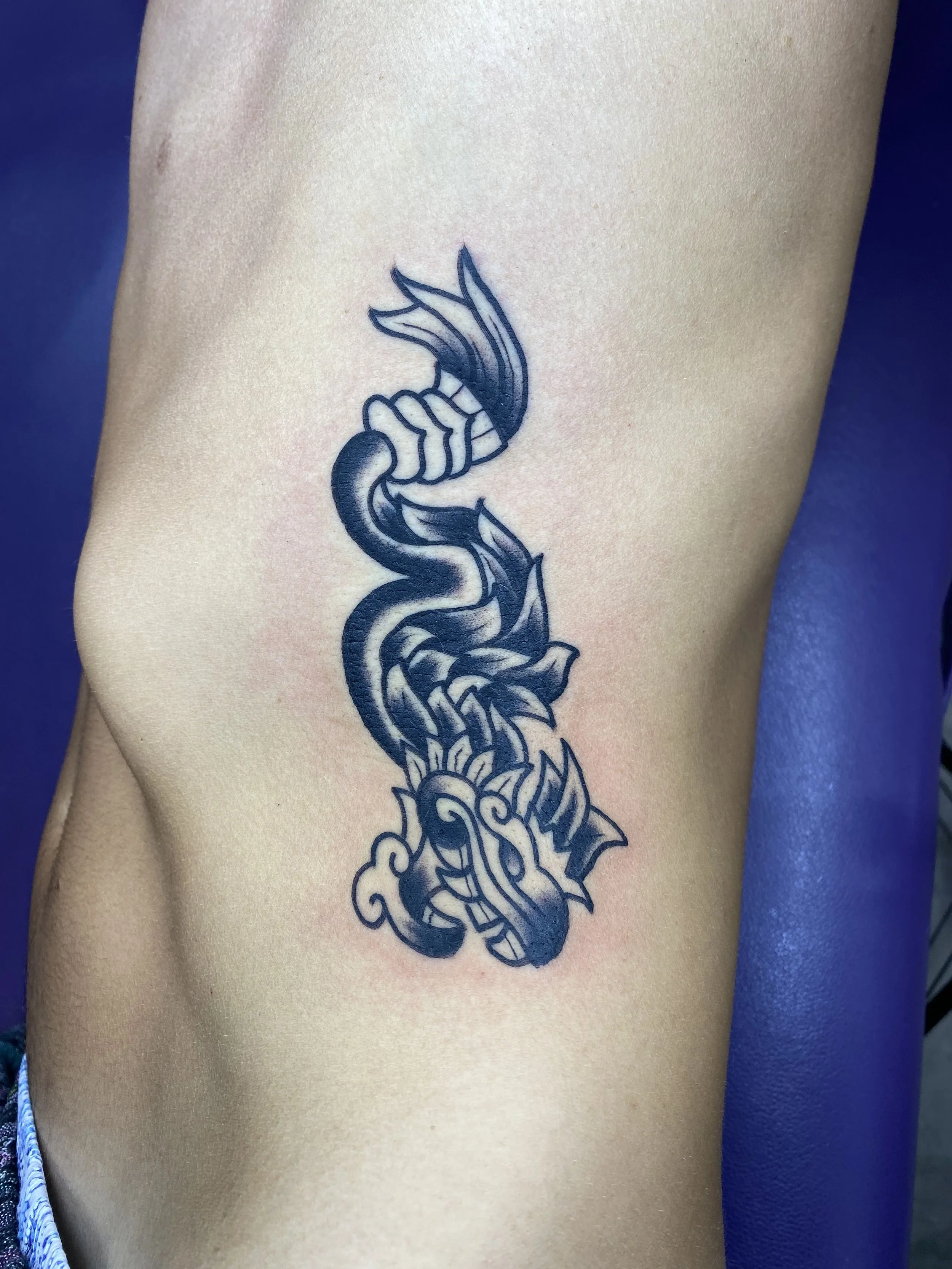 Tattoo of a stylized dragon on a person's arm.