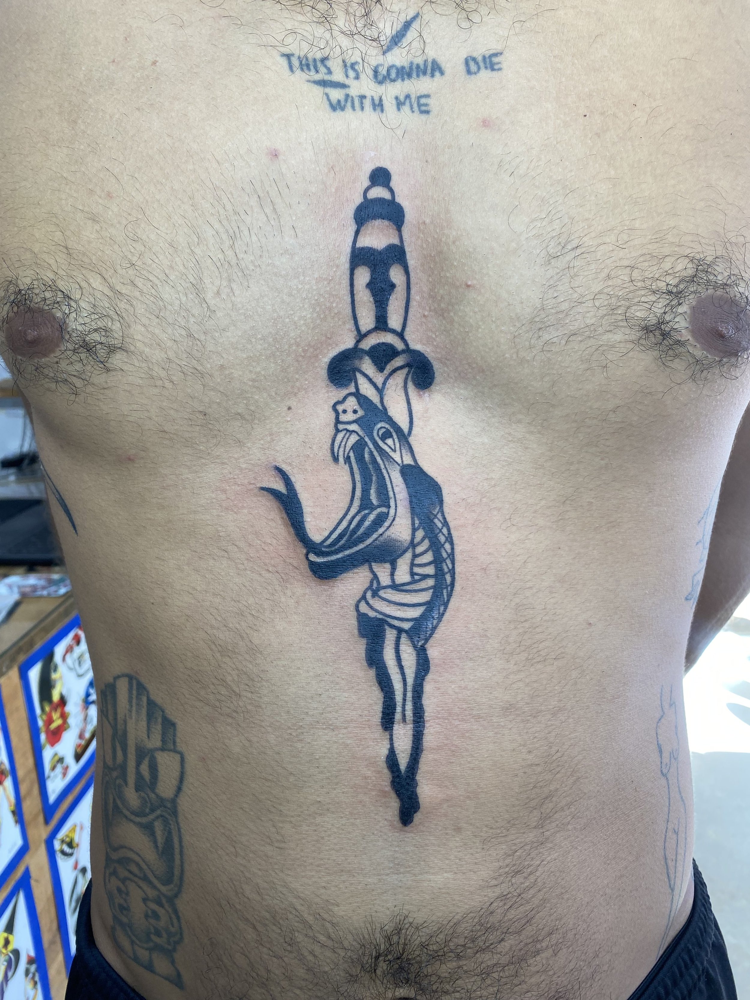 Tattoo of a cartoon character on a person's chest with the phrase 'Tough is coming, die with me' written above.