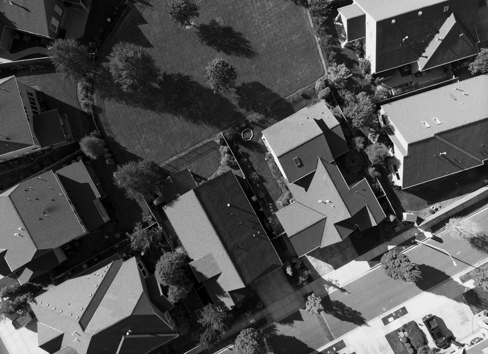 Aerial view of neighborhood houses and a park area with trees in black and white.