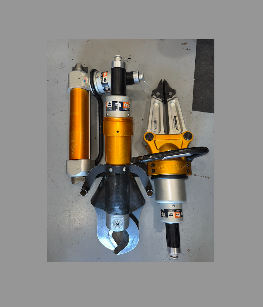 A collection of holmatro extrication tools otherwise known as the jaws of life. cutters, spreaders, and a ram.