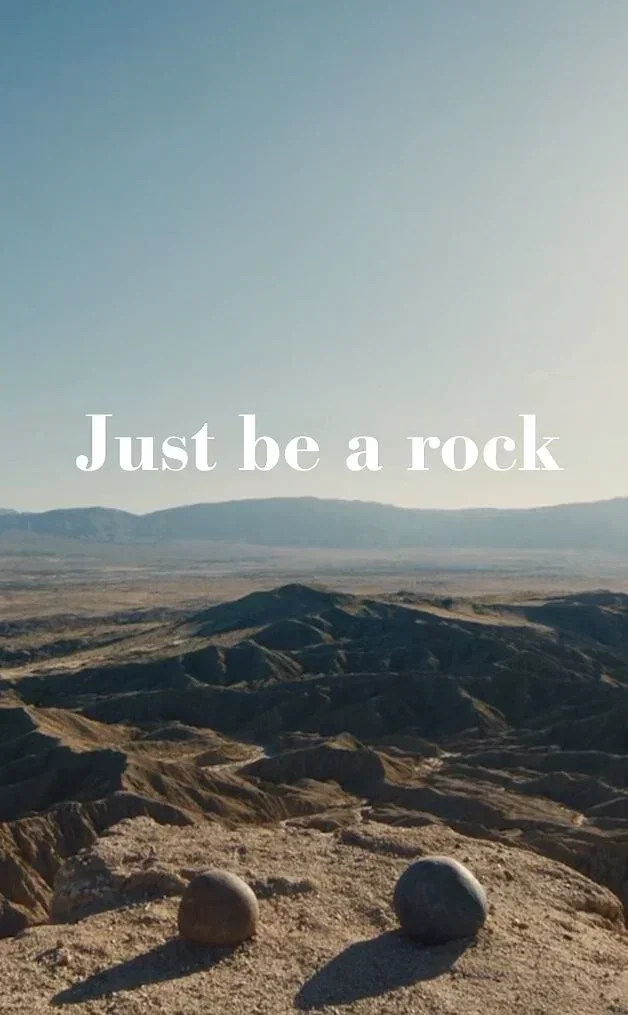 an image of two rocks overlooking a canyon with the phrase 'just be a rock' shown above them in the sky.  the image is from the film Everything, Everywhere, All at Once