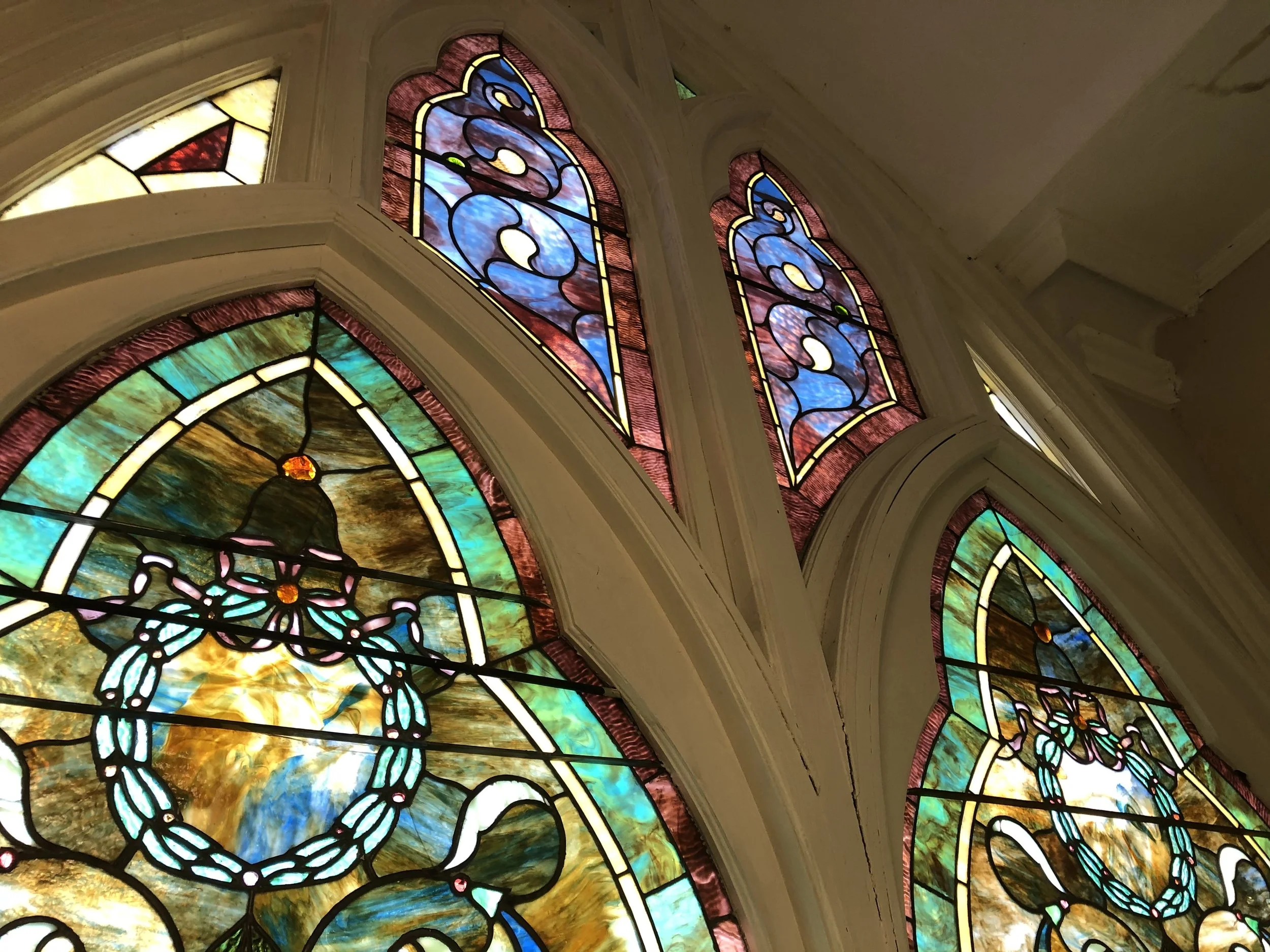 Colorful stained glass windows depicting angels and religious symbols inside a church.