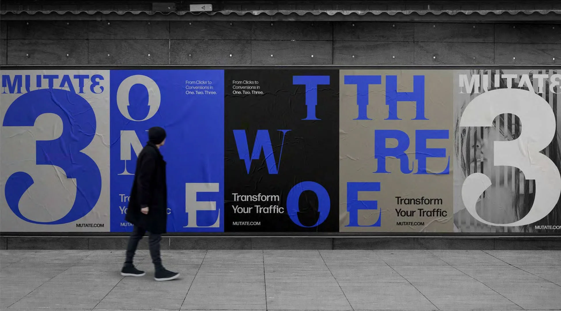 A person walking in front of a large on a wall with bold text and numbers promoting traffic transformation. The wall features a combination of black, beige, blue, and white colors with large numbers 3 and 3, and words about converting clicks to conversions.