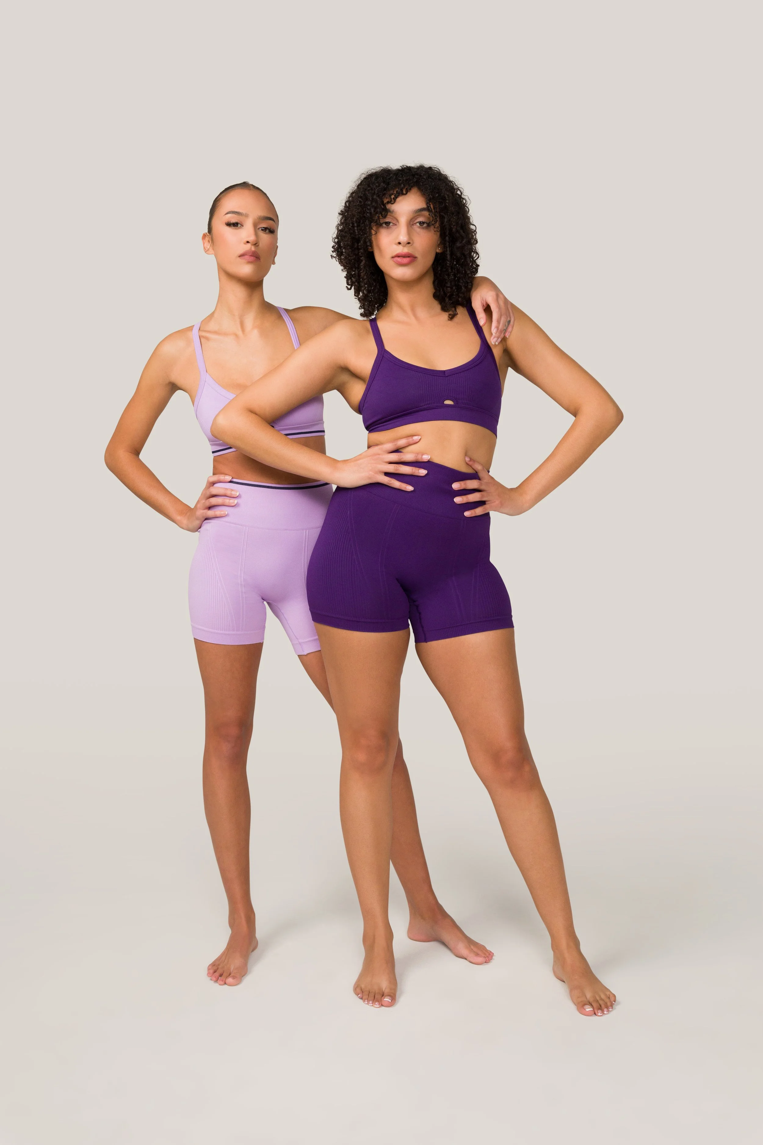 Two women in workout clothes posing confidently against a plain background.