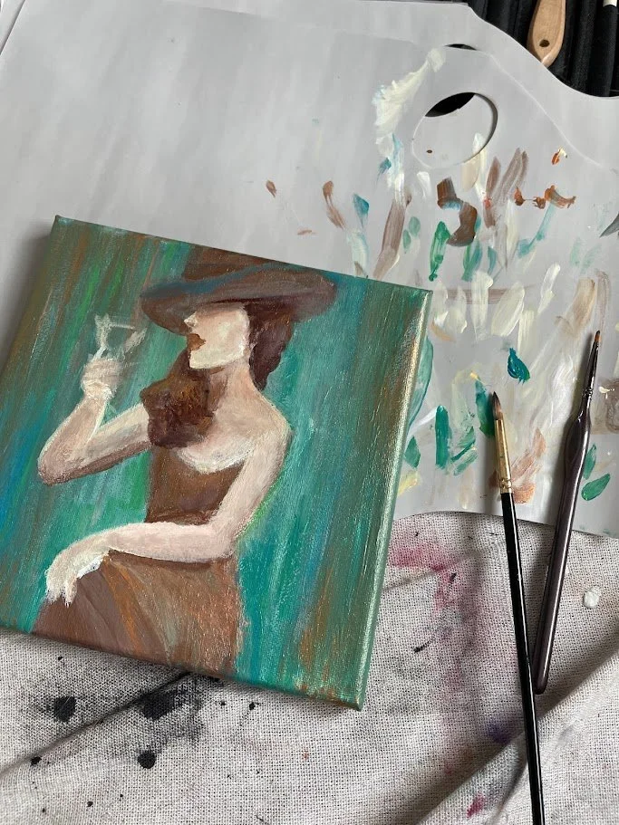 Original painting in progress by Alicia Maye. Woman in wide brim hat, painting tools and palette visible.