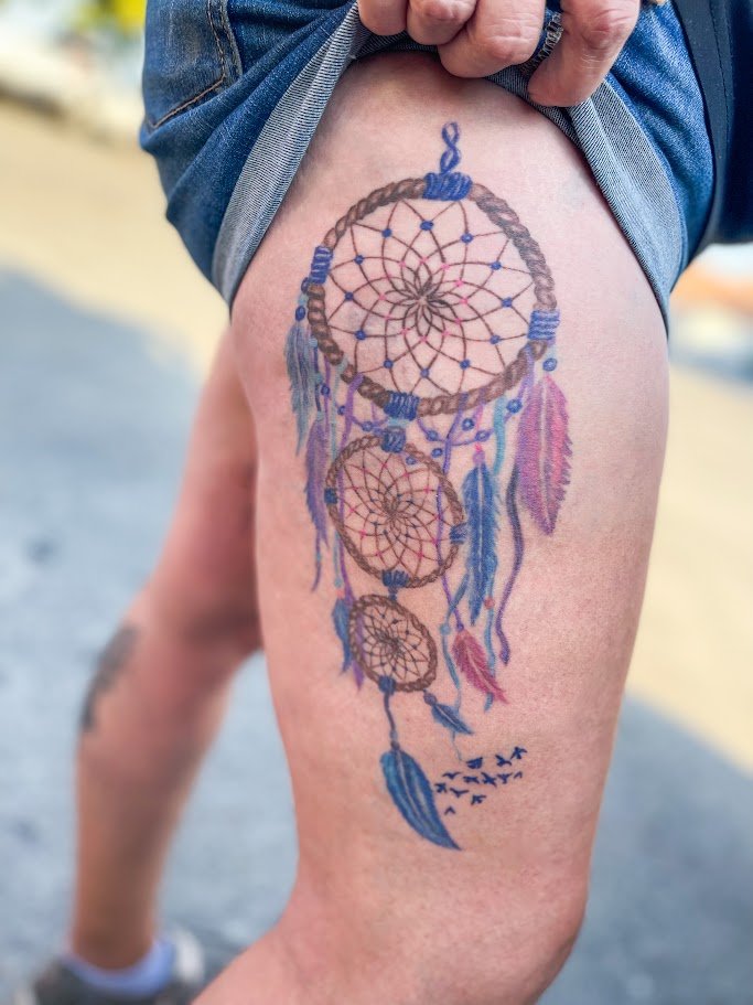 Dreamcatcher healed tattoo by Alicia Maye. Pink, purple, and blue feathers, color realism, upper thigh placement.