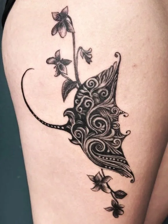 Tattoo of a butterfly with floral details on skin.