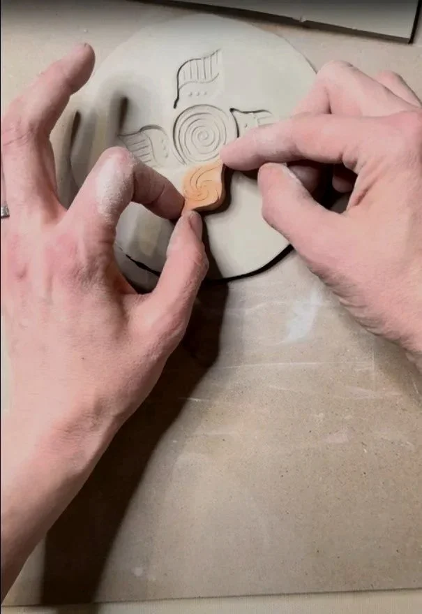Alicia Maye carving an original stamp design into clay for ceramic work.