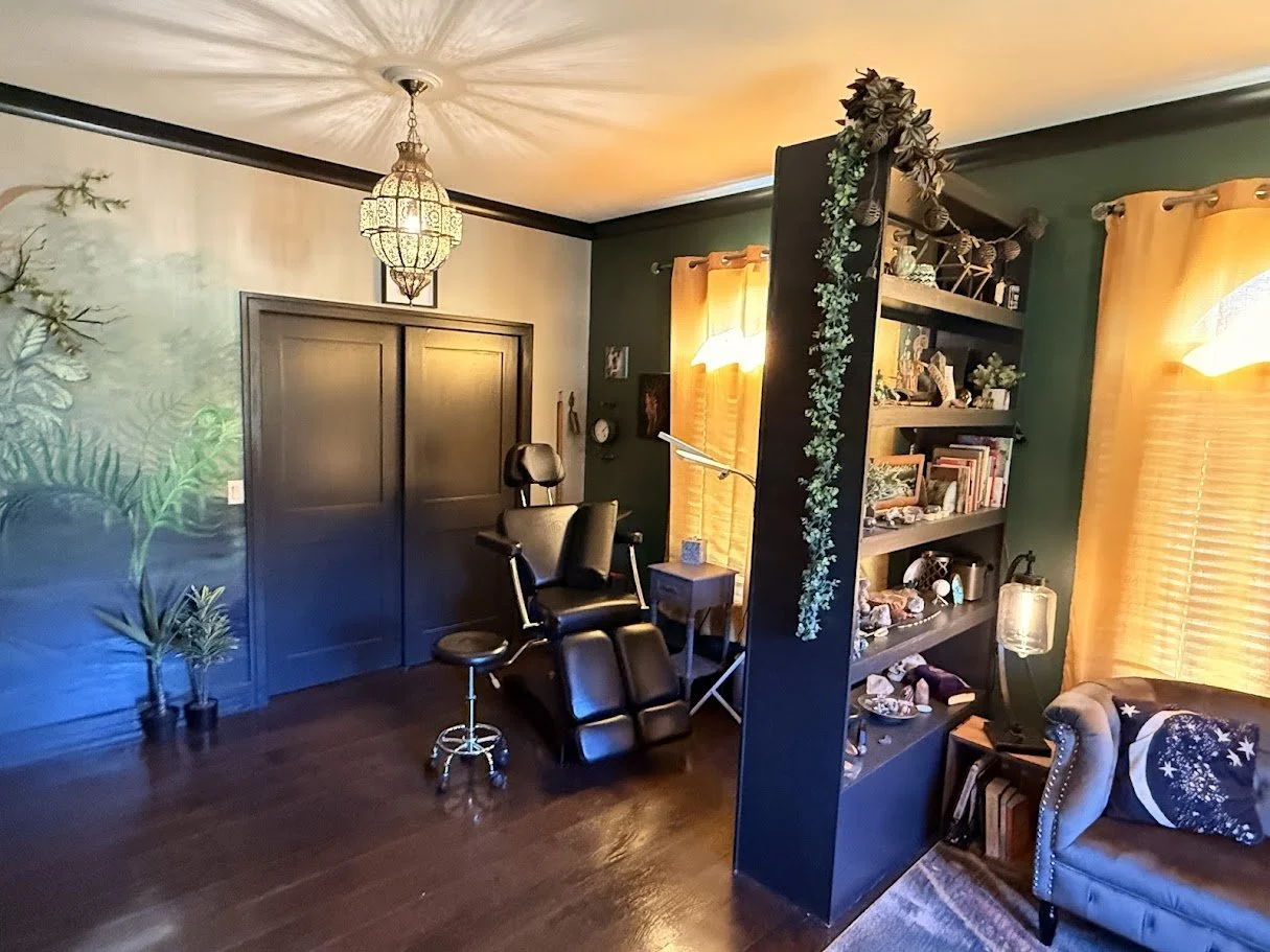Inklinations tattoo studio interior by Alicia Maye. Dark green walls, warm lighting, tattoo chair, chandelier. Private studio Cashmere WA.