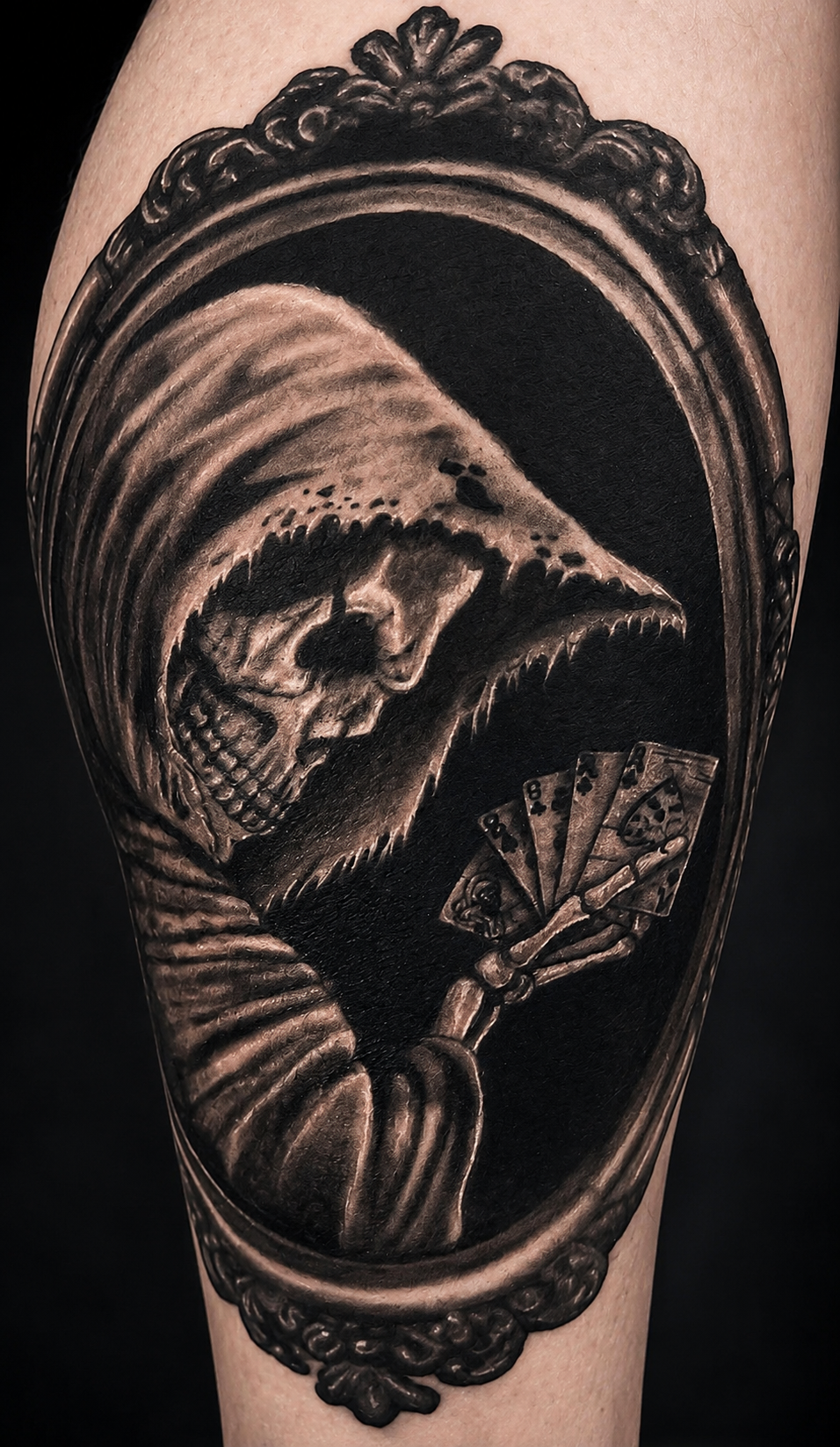 "Dead Man's Hand" — custom tattoo by Alicia Maye. Grim reaper holding aces and eights in black and grey realism, ornate mirror frame. Inklinations private tattoo studio, Cashmere WA.