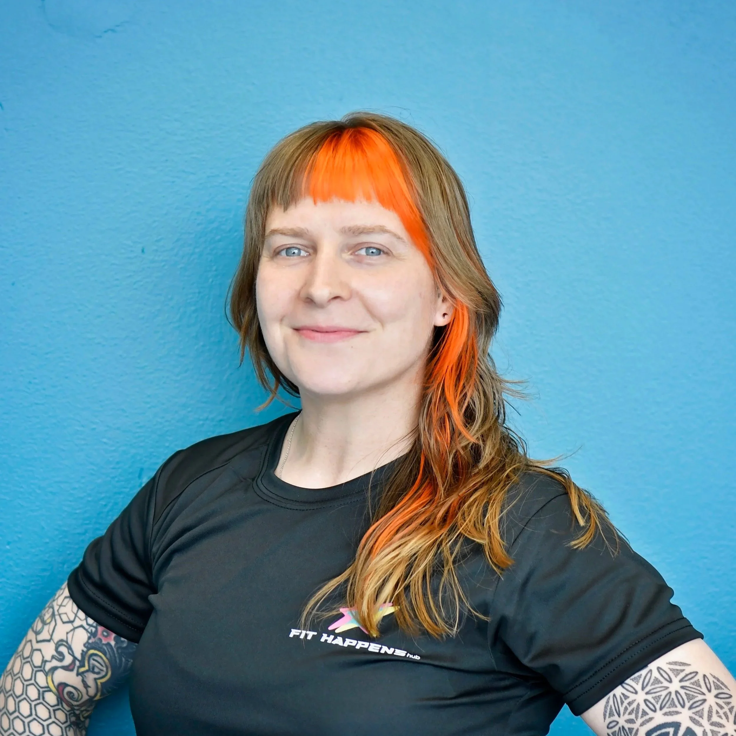 A woman with auburn hair and a white shirt smiling, surrounded by red and white boxing gloves.