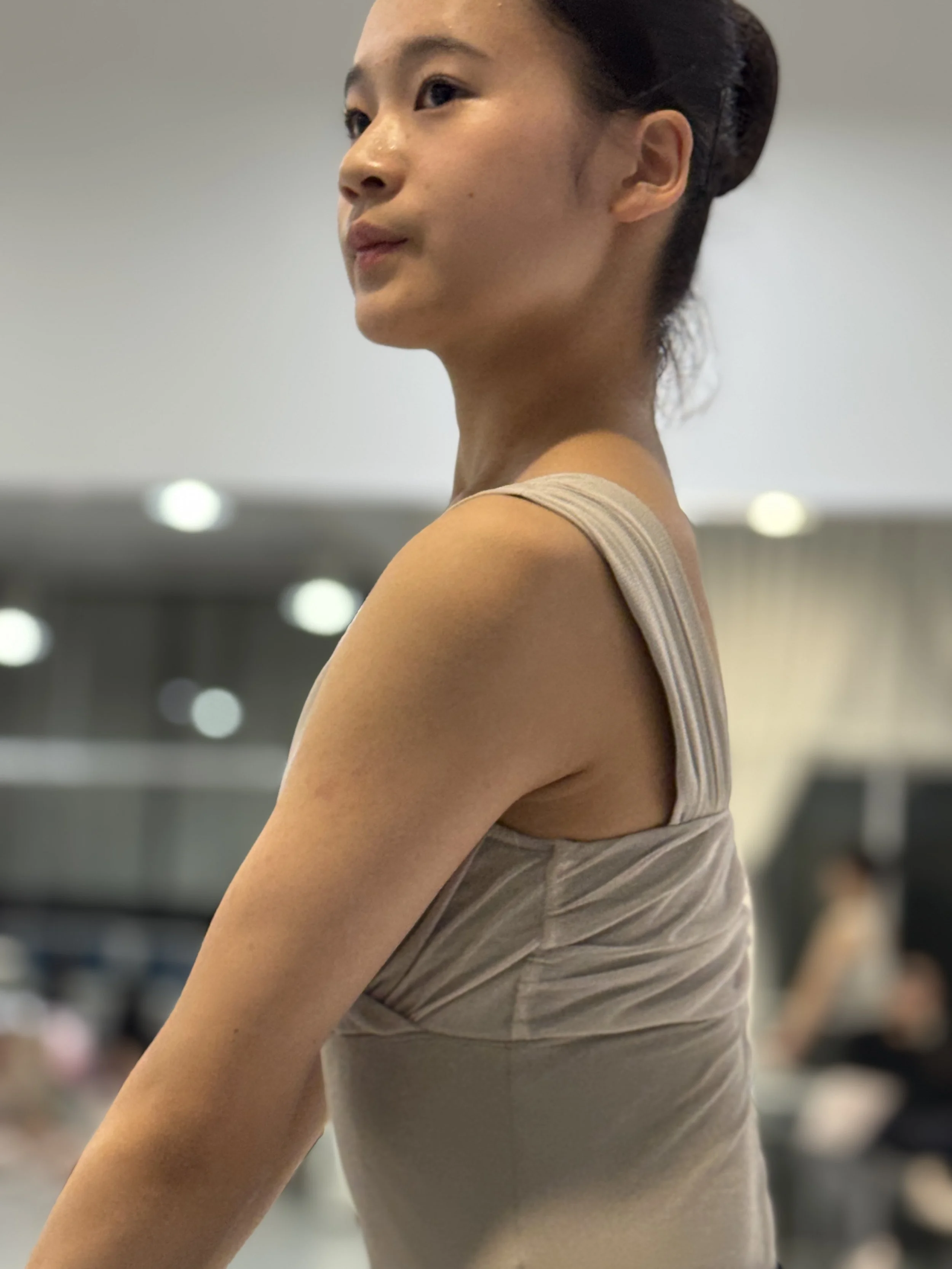 運動する女性の横顔と腕のアップ、ジムかフィットネススタジオの背景
