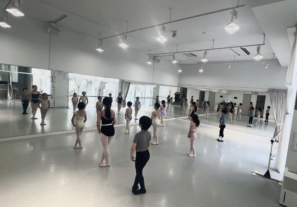 バレエのクラスをしているダンススタジオ。子供たちと先生が鏡の前でレッスンを受けている光景。