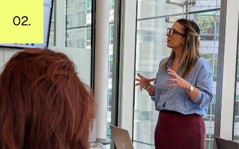 Ash presenting to a team in a modern conference room.