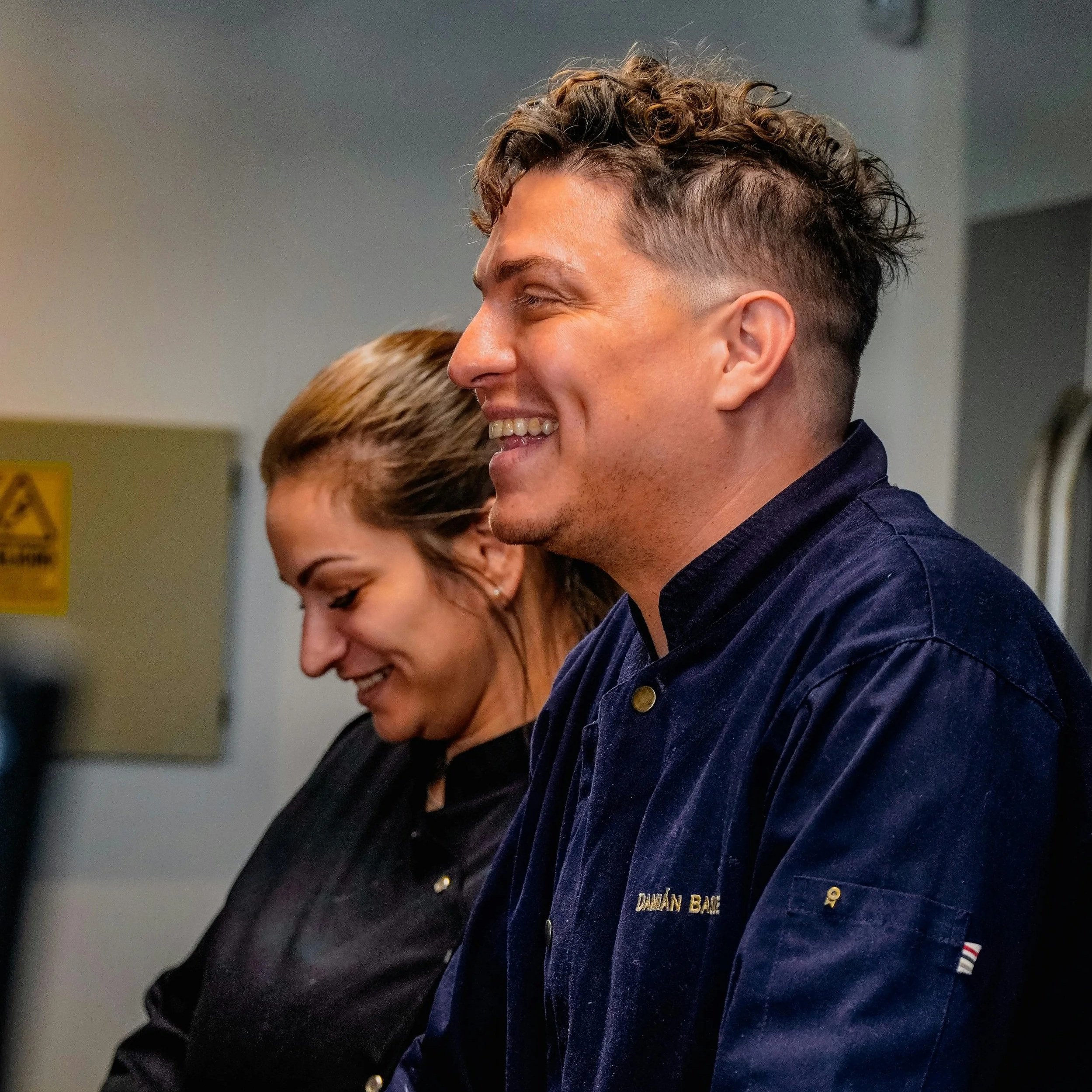 A people leader smiling with a coworker in a commercial kitchen.