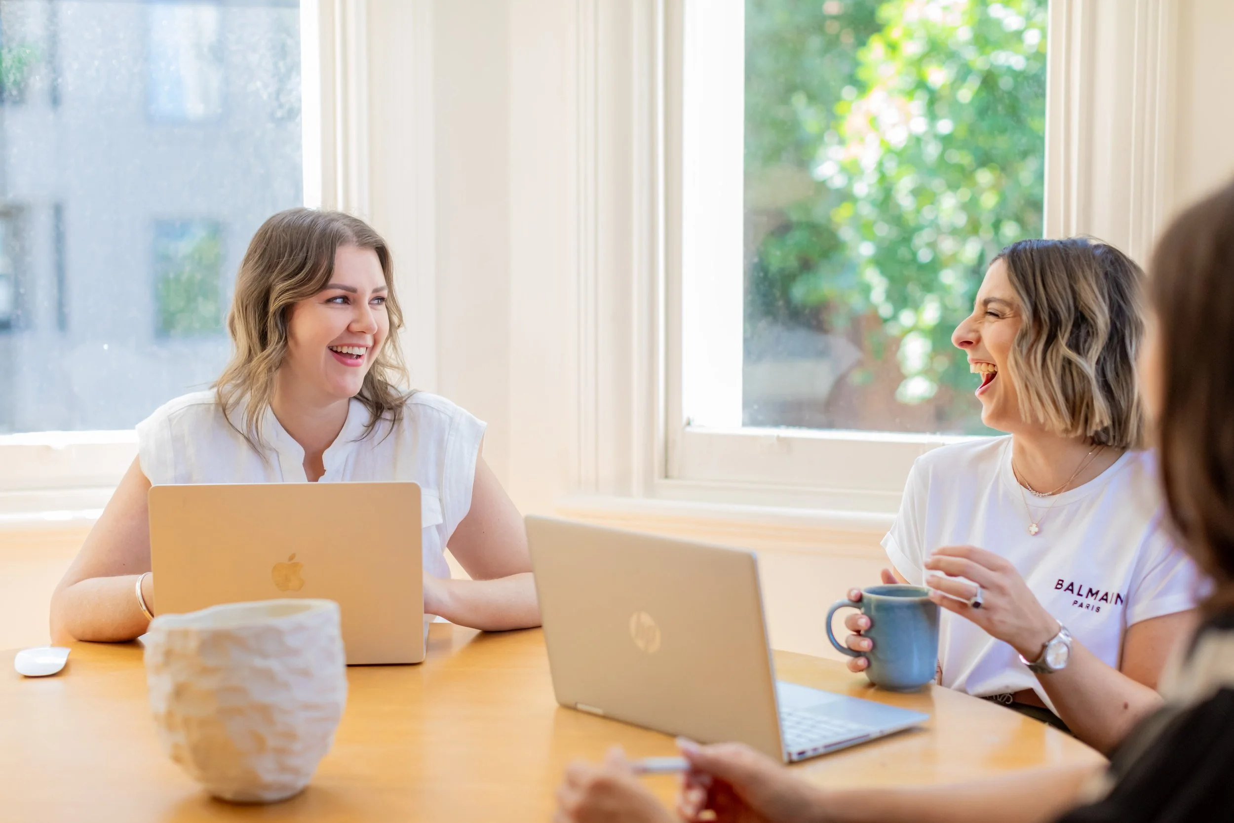 Three People Co. team members laughing together around a table.