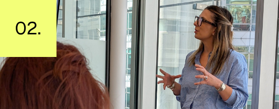 Ash presenting to a team in a modern conference room.