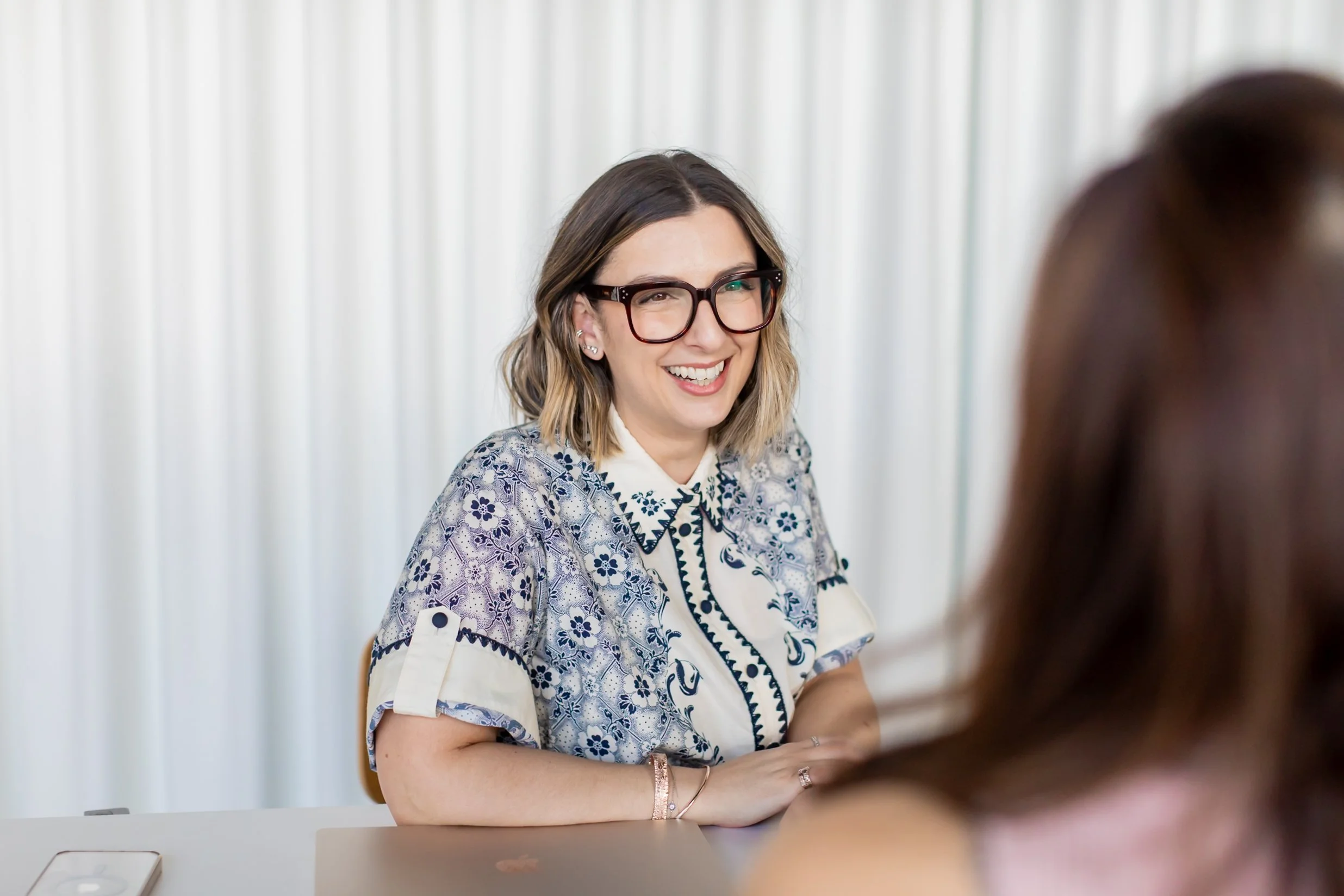 Ash smiling and listening during a workplace one on one conversation.