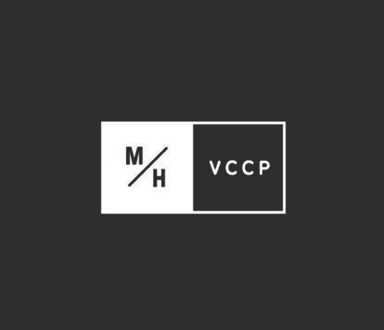 Minimalist logo with two squares; the left square contains the letters 'M' and 'H' separated by a slash, the right square contains the letters 'VCCP'.