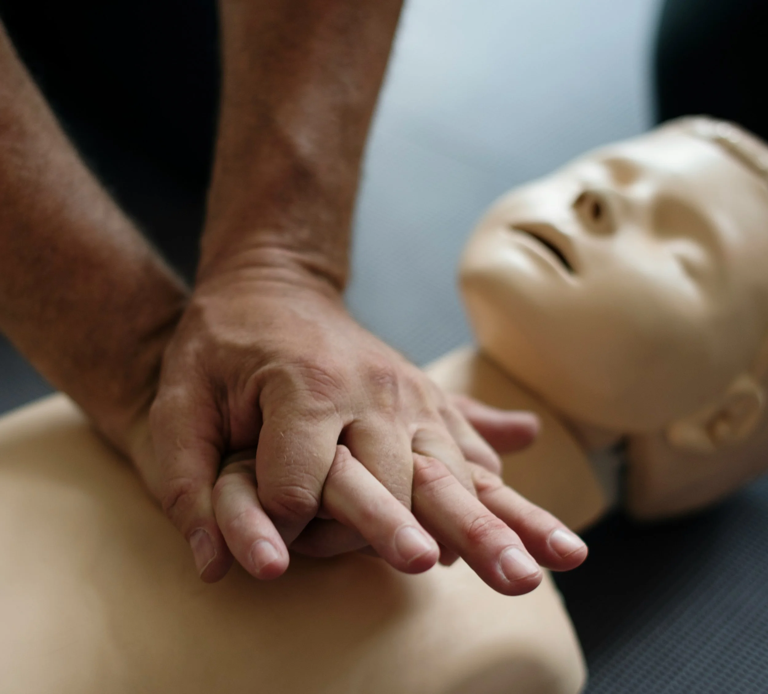 Close-up of two hands, one with darker skin and the other with lighter skin, clasped together. In the background, a beige mannequin head with facial features is seen.