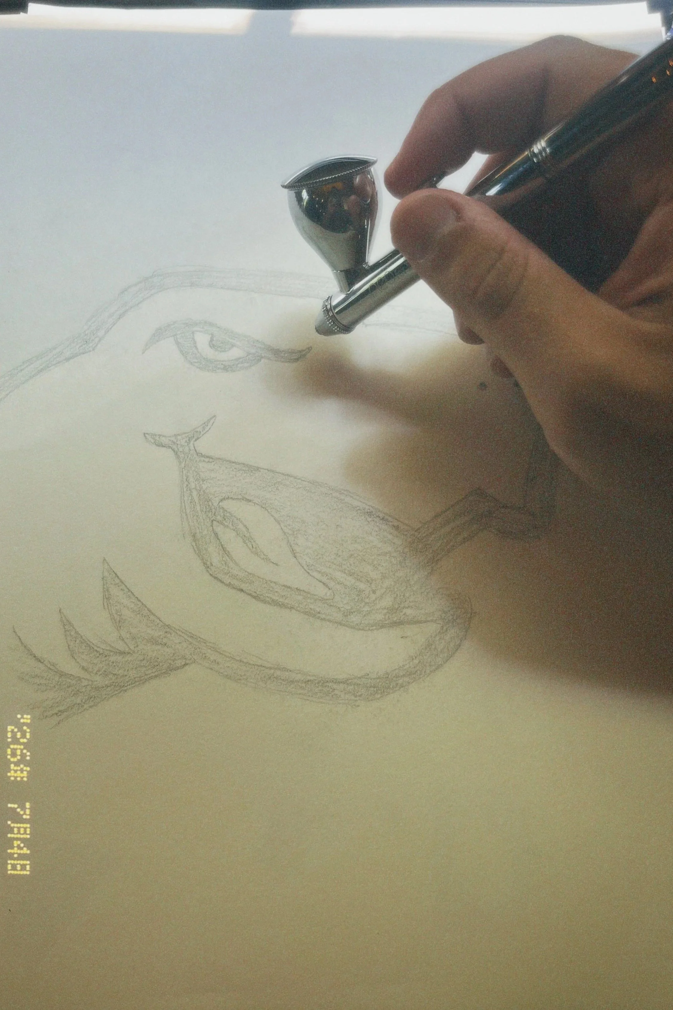 A hand holding a pen is sketching a face on paper, focusing on the eye and nose area.
