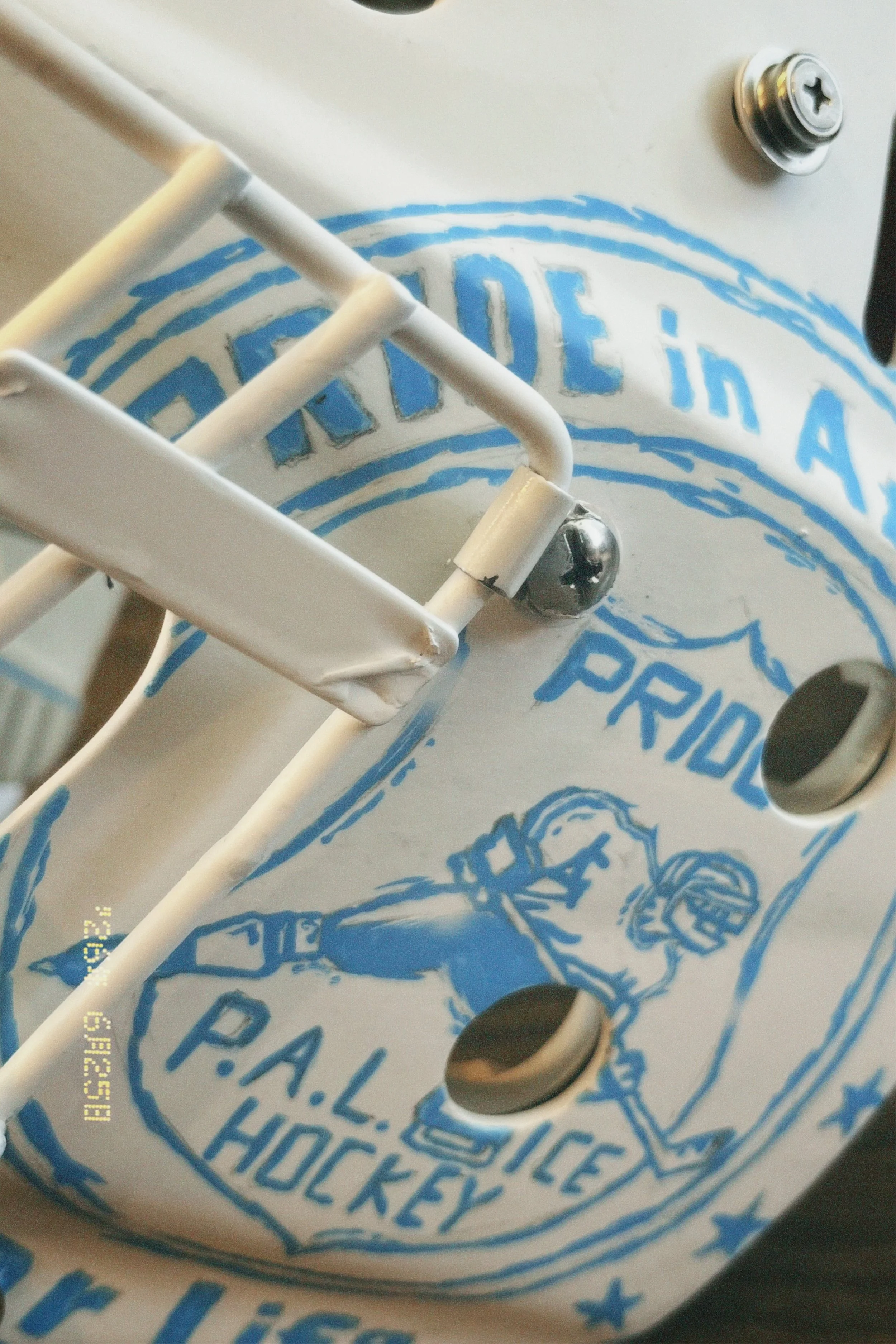 Close-up of a hockey puck on a paper bag with blue printing that reads "Hockey." There is a white metal frame partially obscuring the view and a metal screw on the bag.