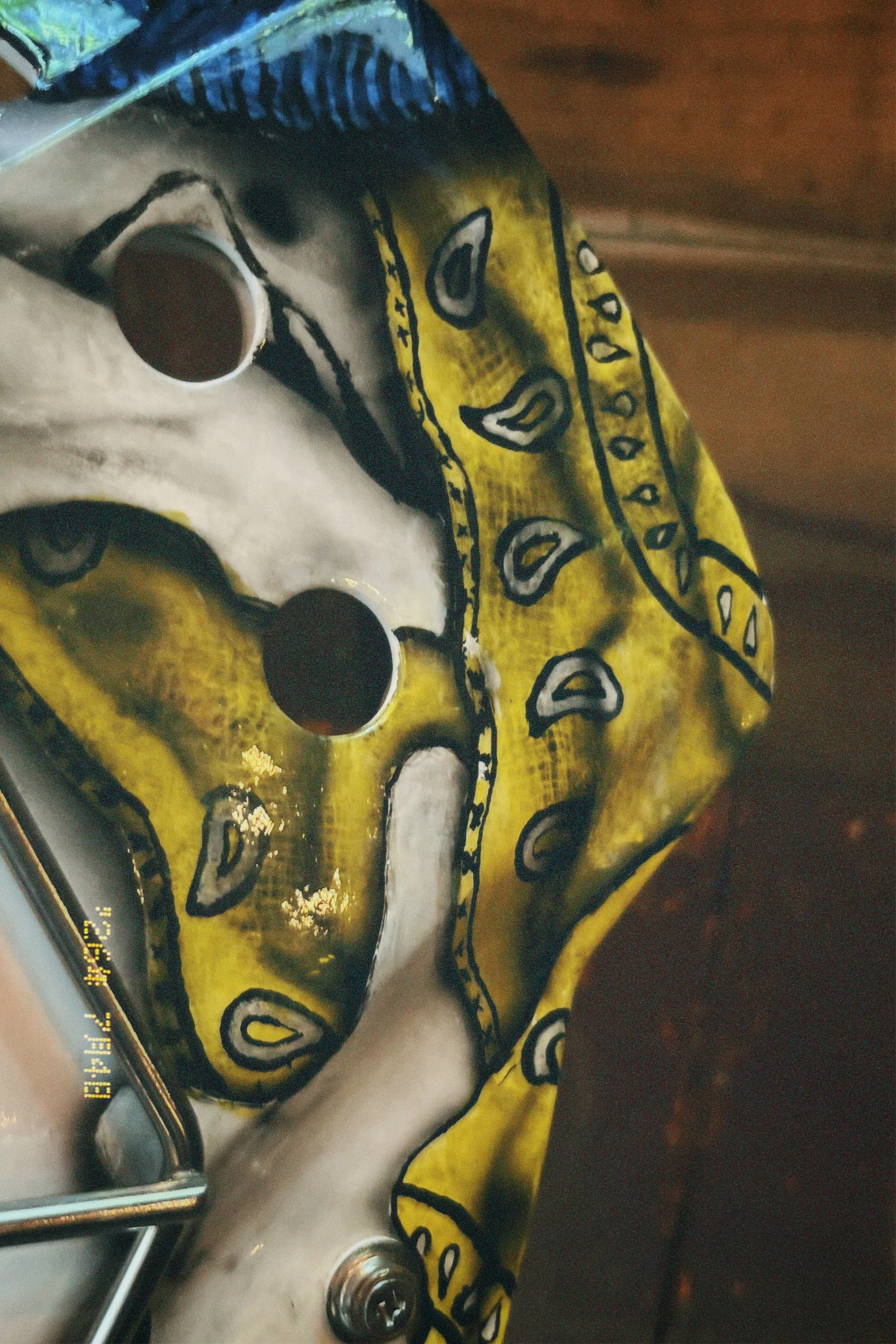 Close-up of a painted decorative skull with yellow, black, white, and blue colors, featuring detailed patterns and design elements.