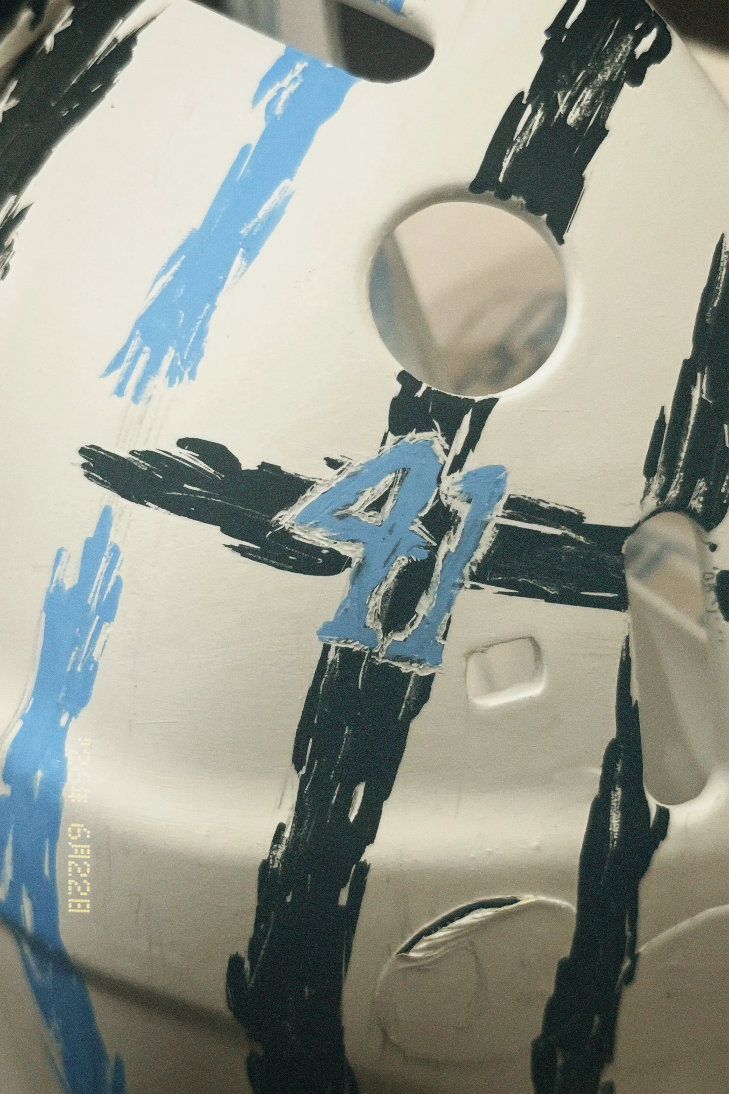 Close-up of a painted surface with black and blue streaks on a white background.