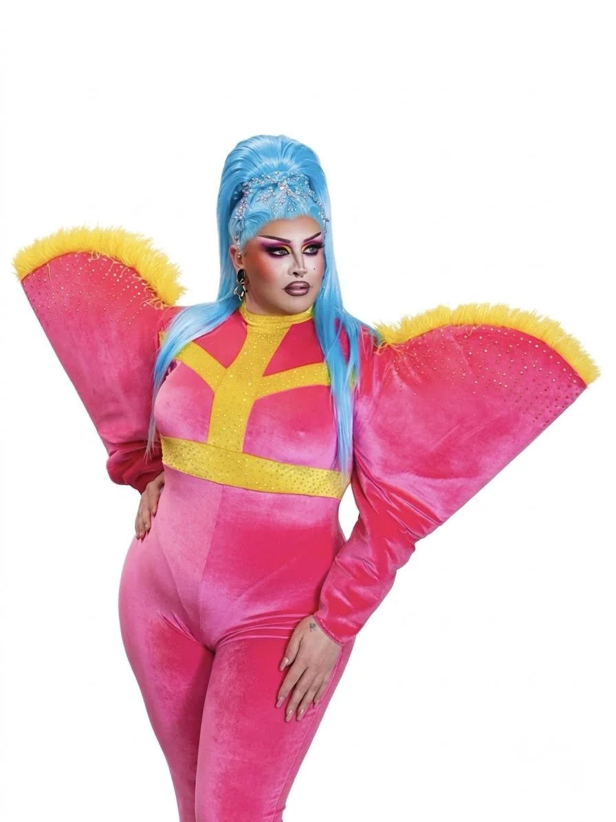 A person with bright blue hair in an elaborate, colorful outfit with large pink sleeves and yellow accents, standing against a plain white background.