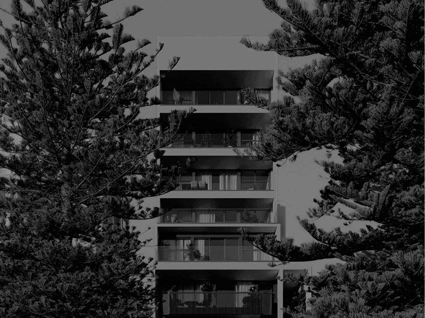 A modern multi-story apartment building viewed through pine trees.