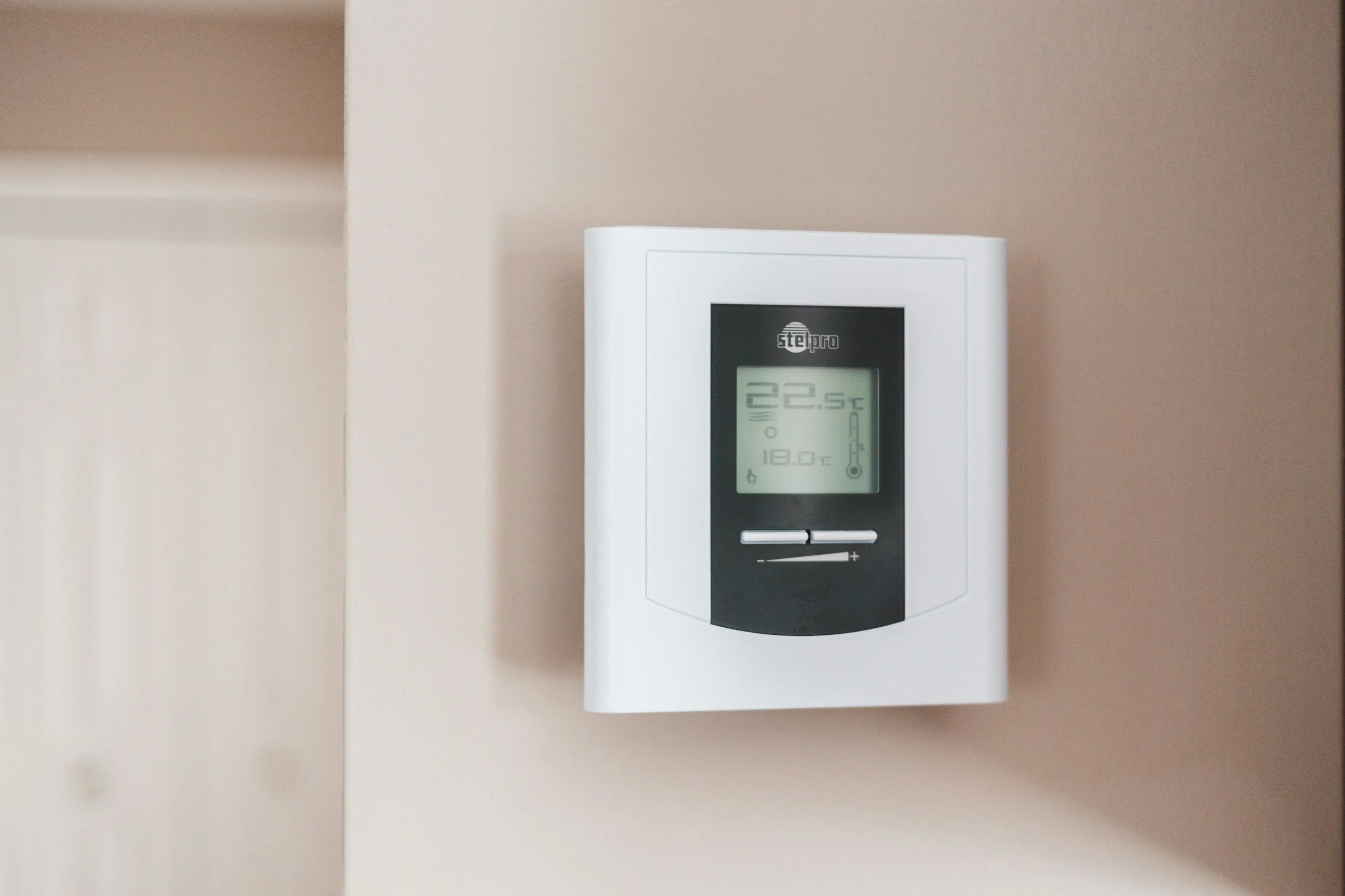A digital thermostat mounted on a wall displaying the temperature as 22.5 degrees Celsius.